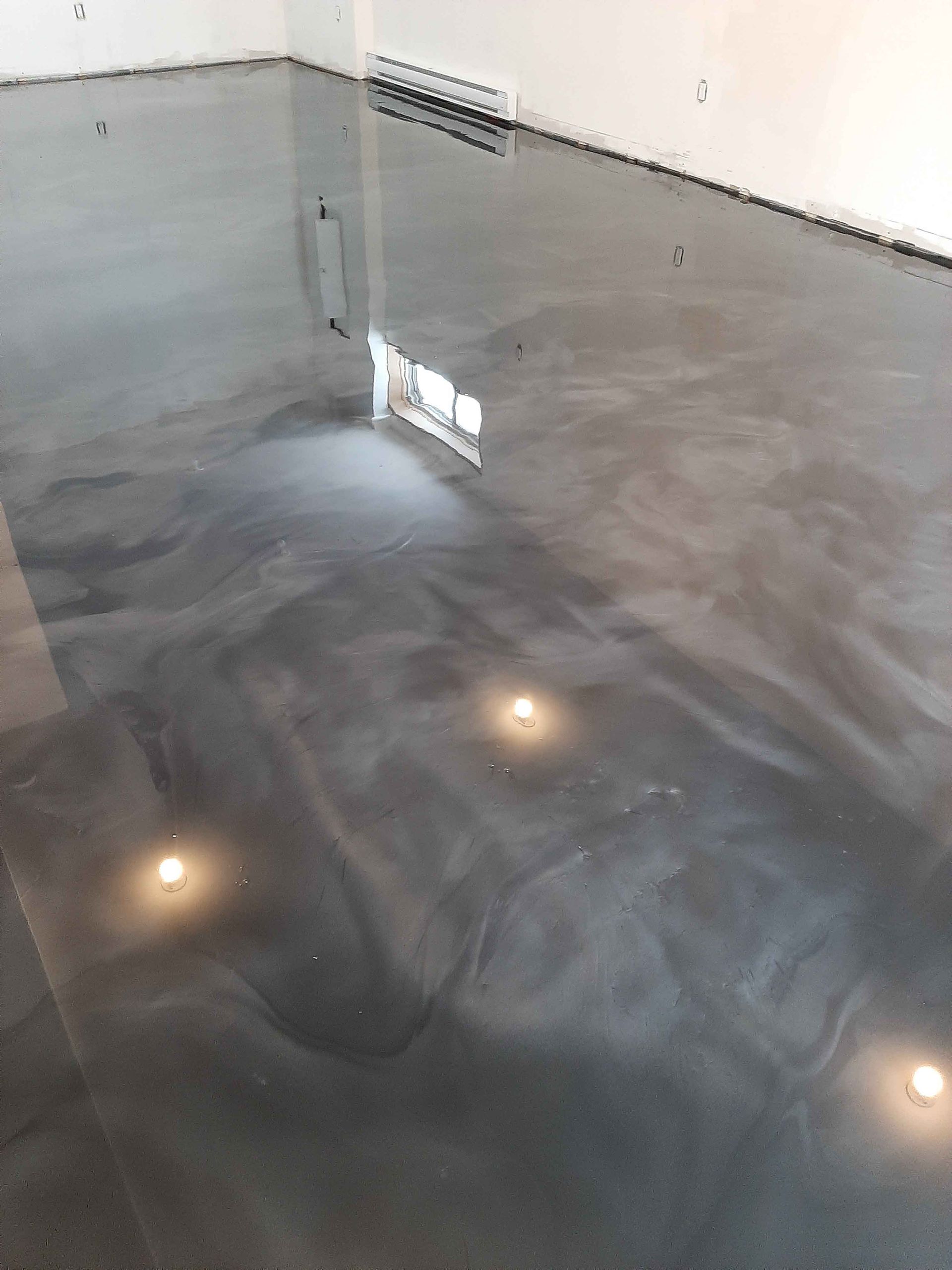 Un sol métallique brillant dans une pièce avec le reflet d'une fenêtre.