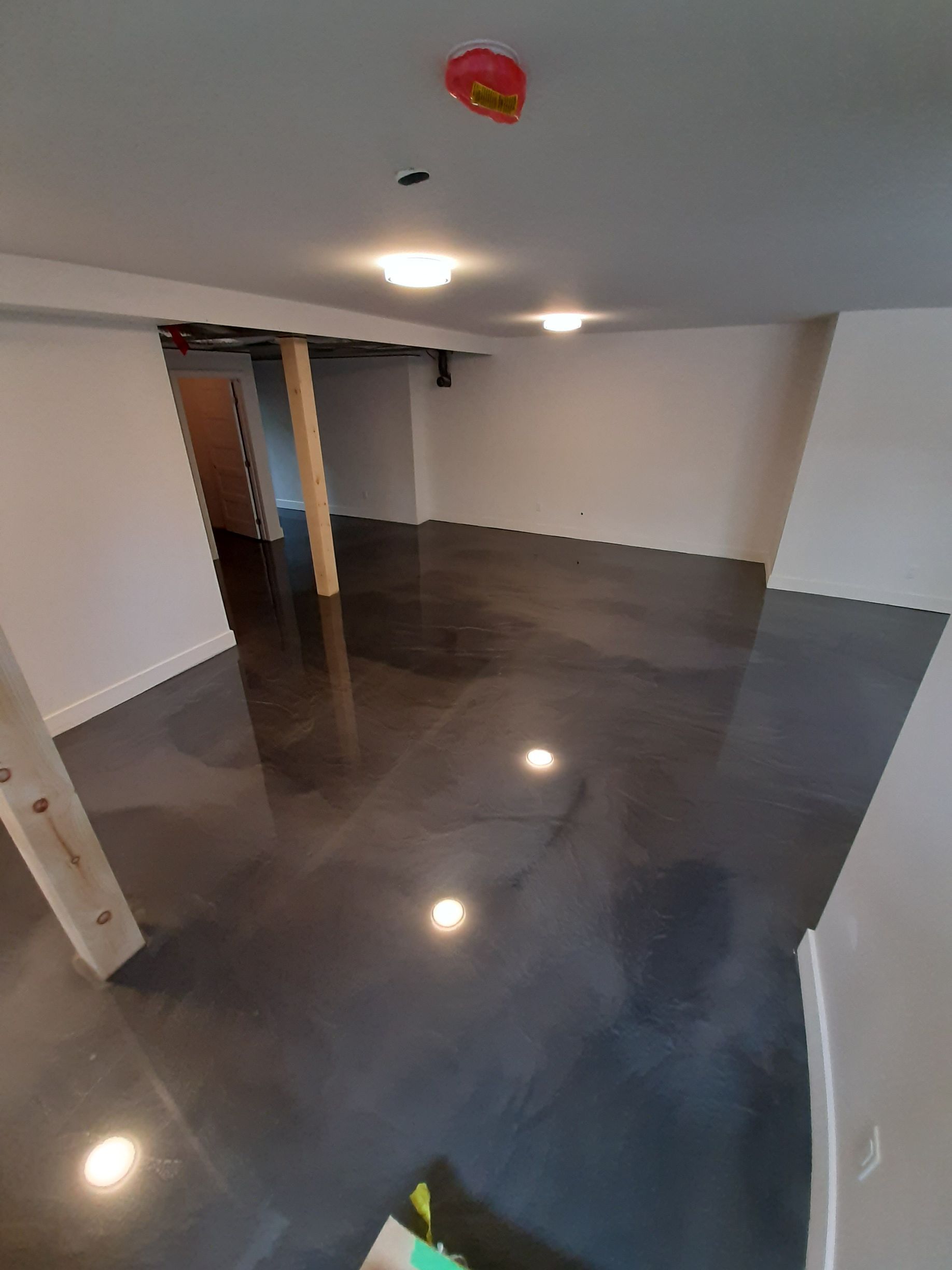 Un sous-sol avec un sol en béton brillant et des murs blancs.