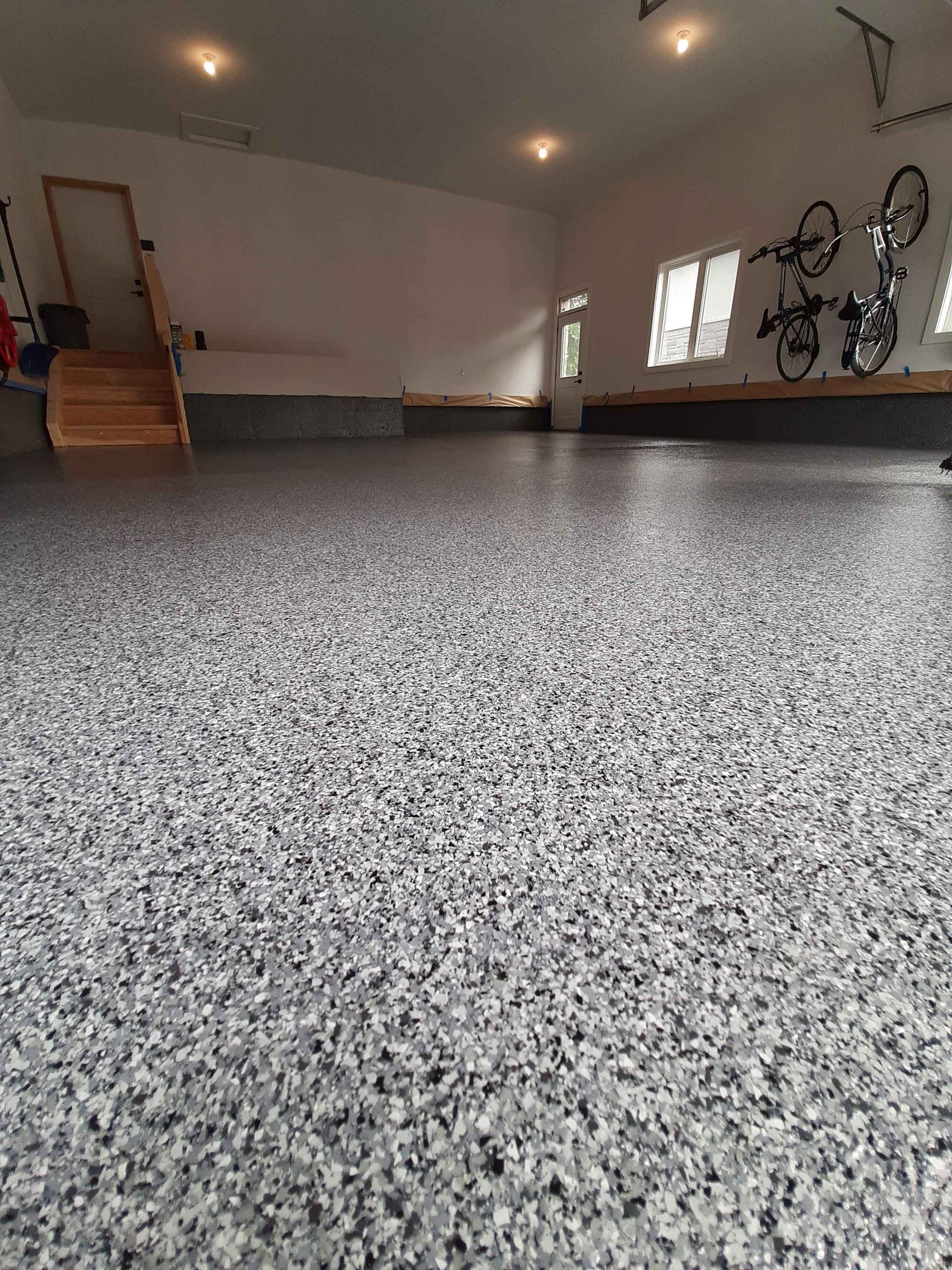 Un garage avec un sol en béton et des vélos au mur.