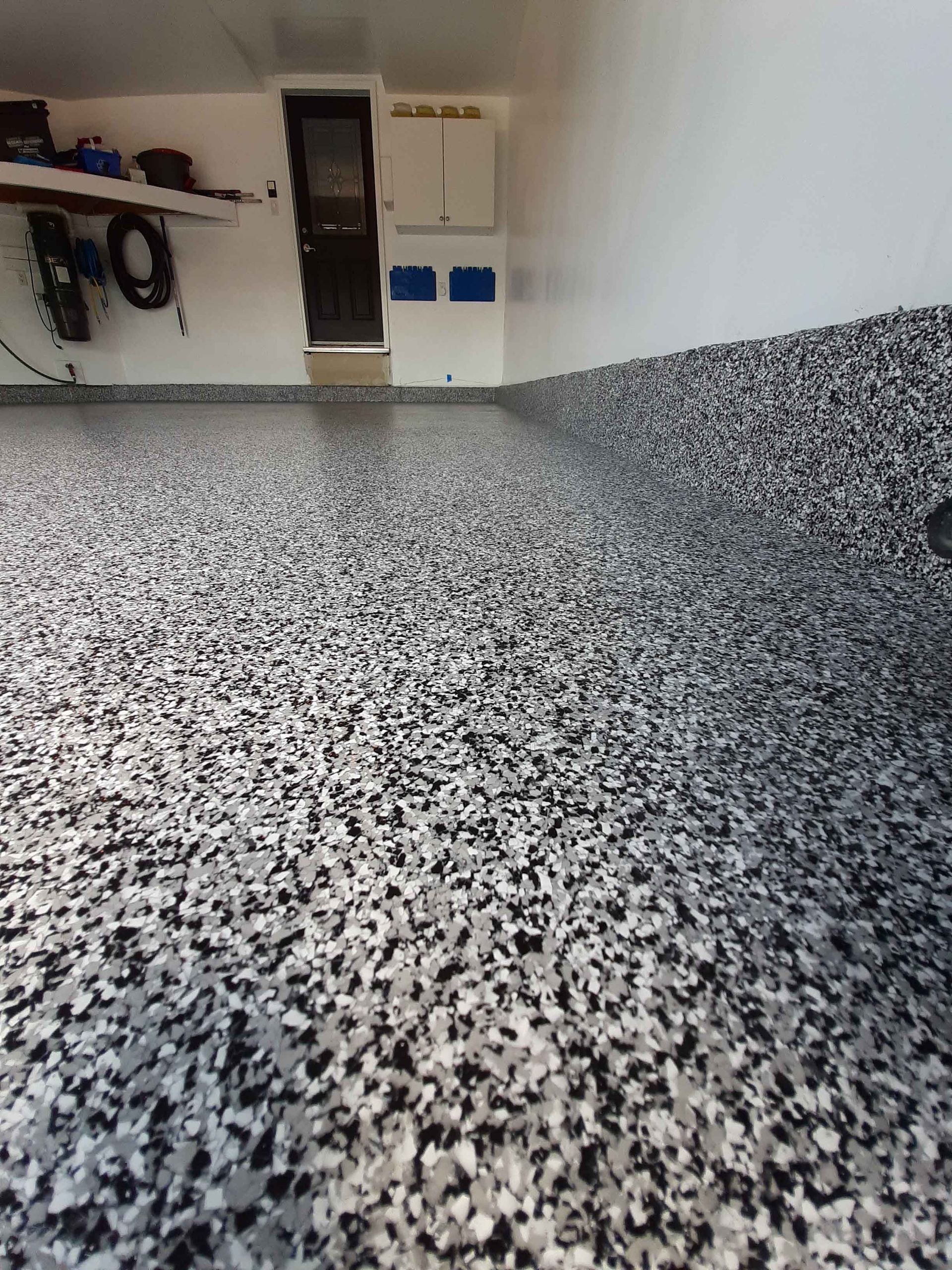 Un garage avec un sol noir et blanc et un mur blanc.