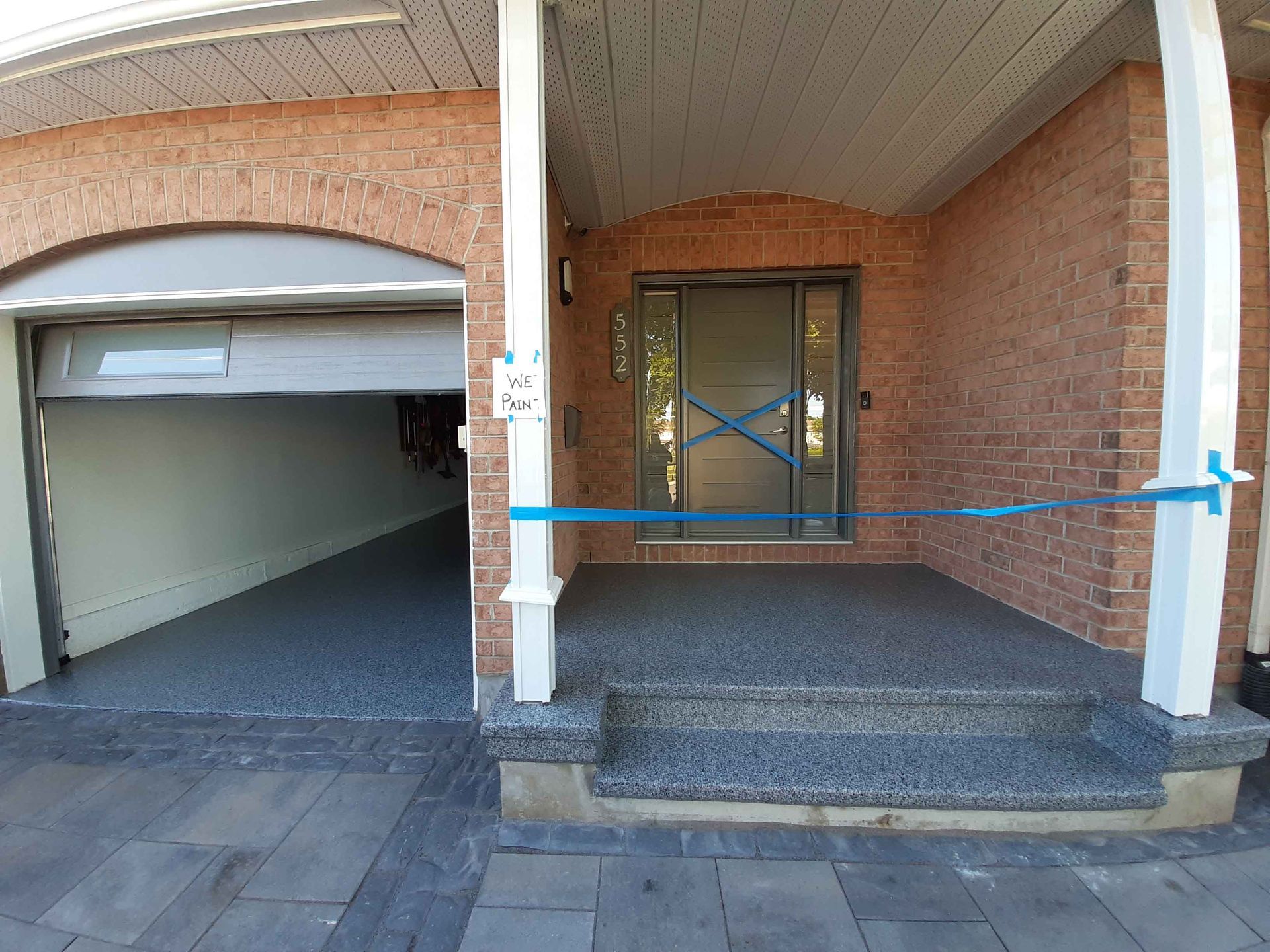 Une maison en briques avec un garage et un porche avec du ruban bleu dessus.