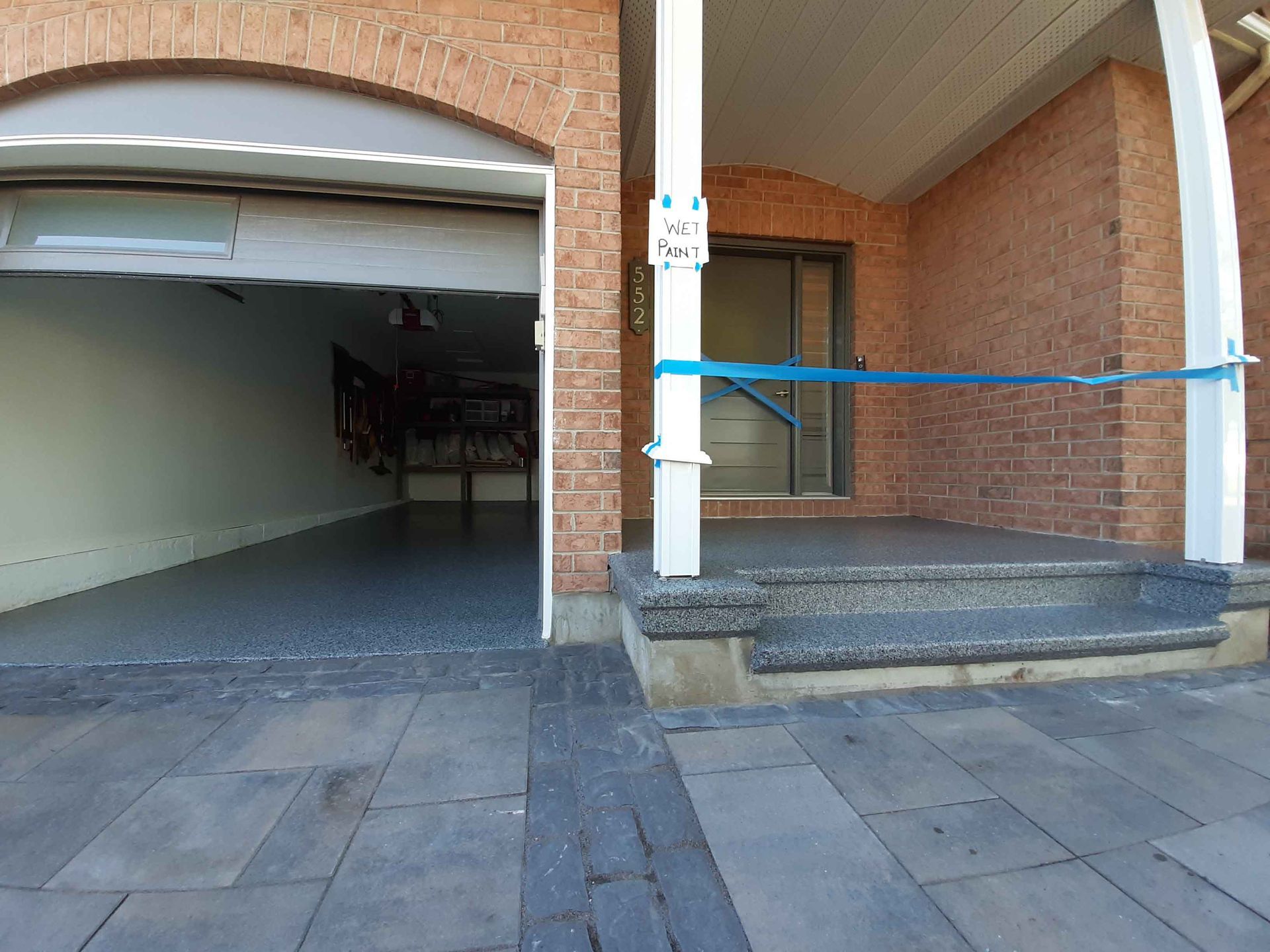 Une maison en briques avec une porte de garage ouverte et des escaliers qui y mènent.