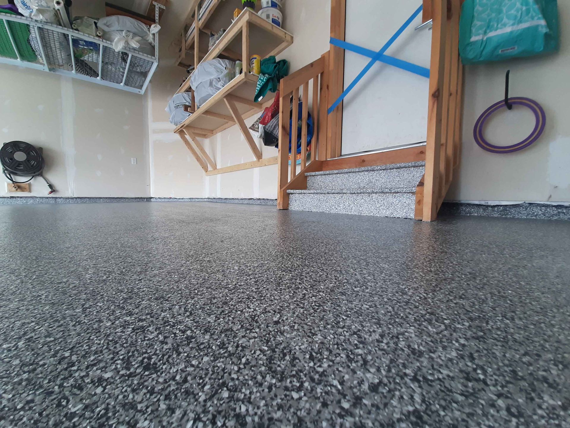 Un garage avec un sol gris et un escalier en bois.