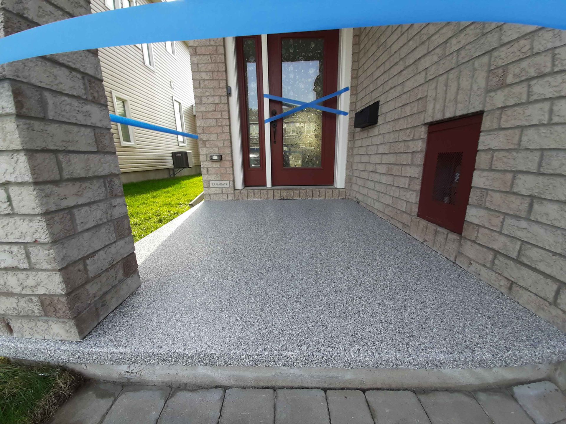 Un porche d'entrée d'une maison en briques avec un ruban bleu recouvrant la porte.