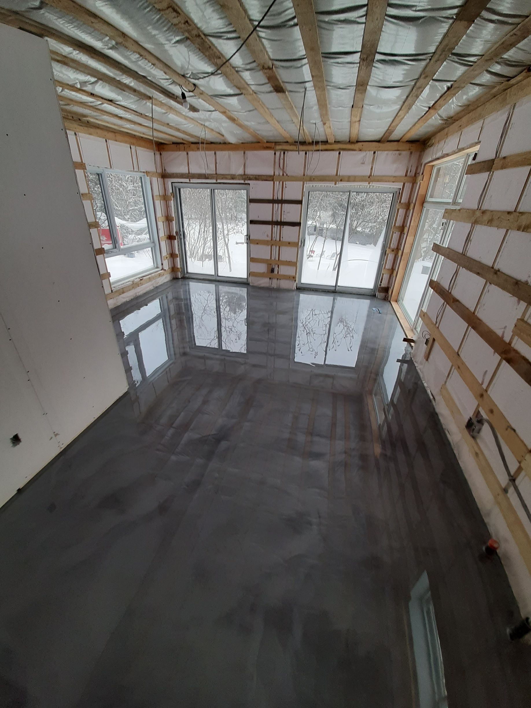 Une grande pièce avec un sol en béton et des portes coulissantes en verre.