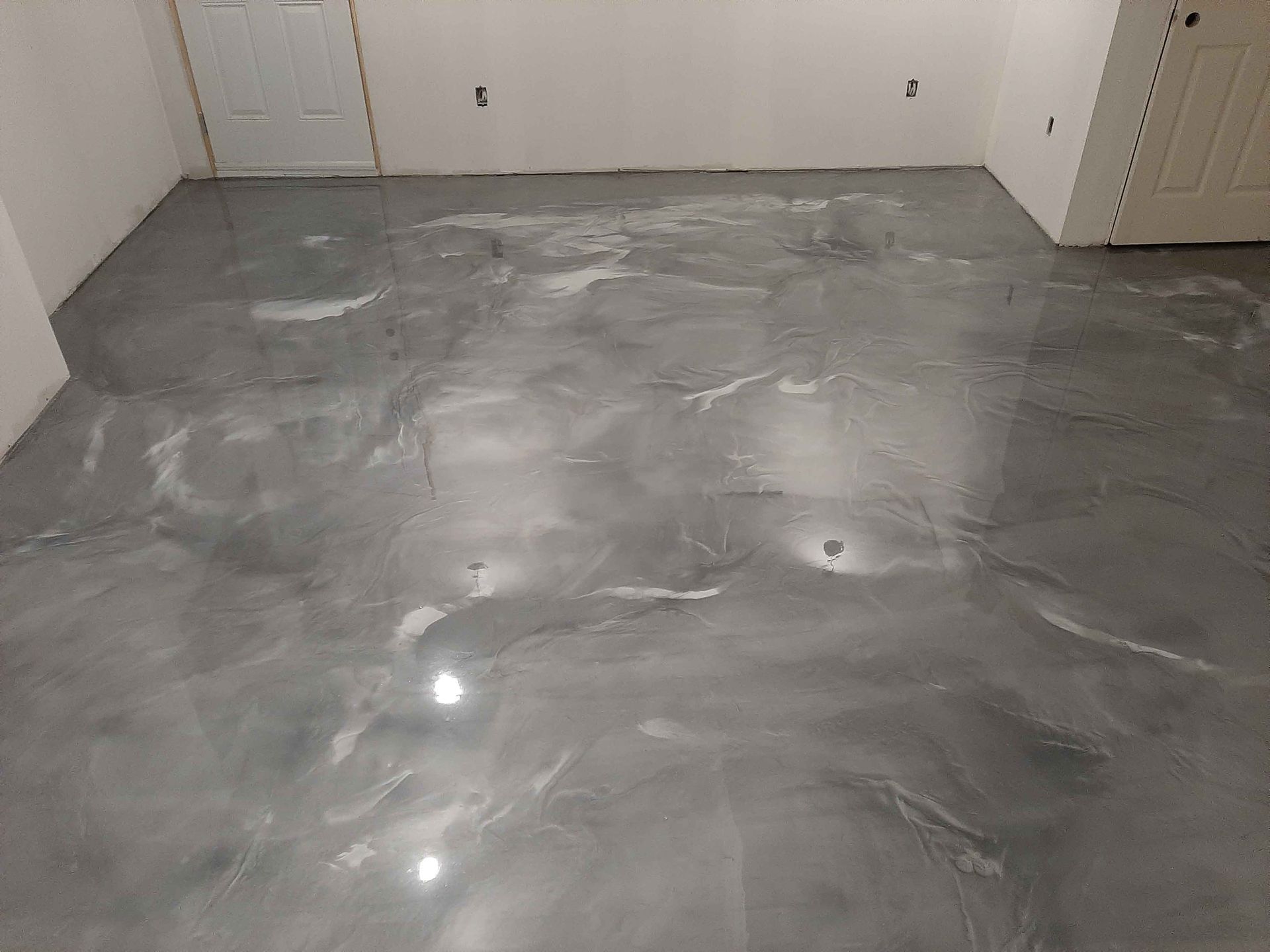 Une pièce avec un sol métallique brillant et une porte.