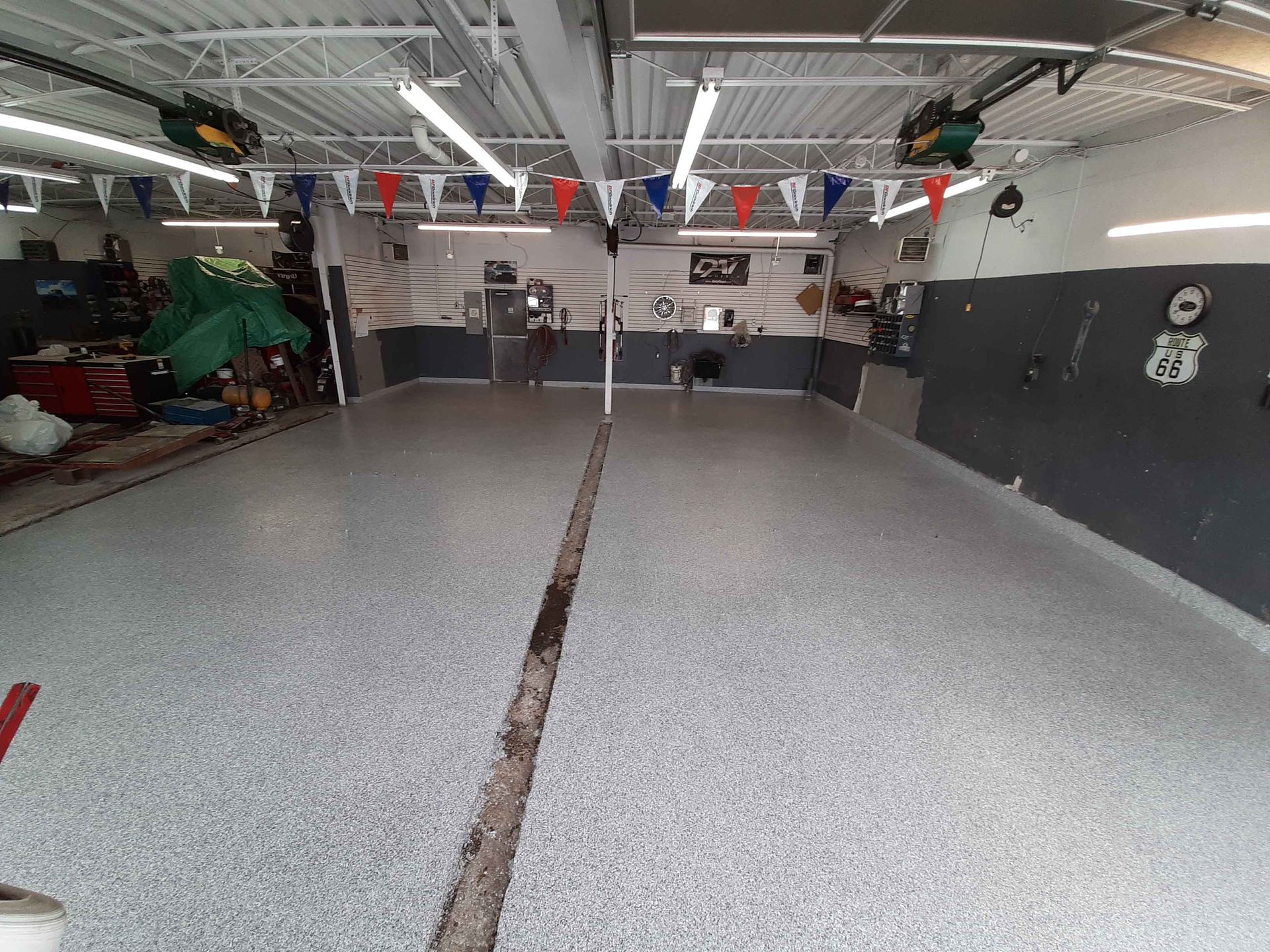 Un garage avec un sol en béton et des drapeaux suspendus au plafond.