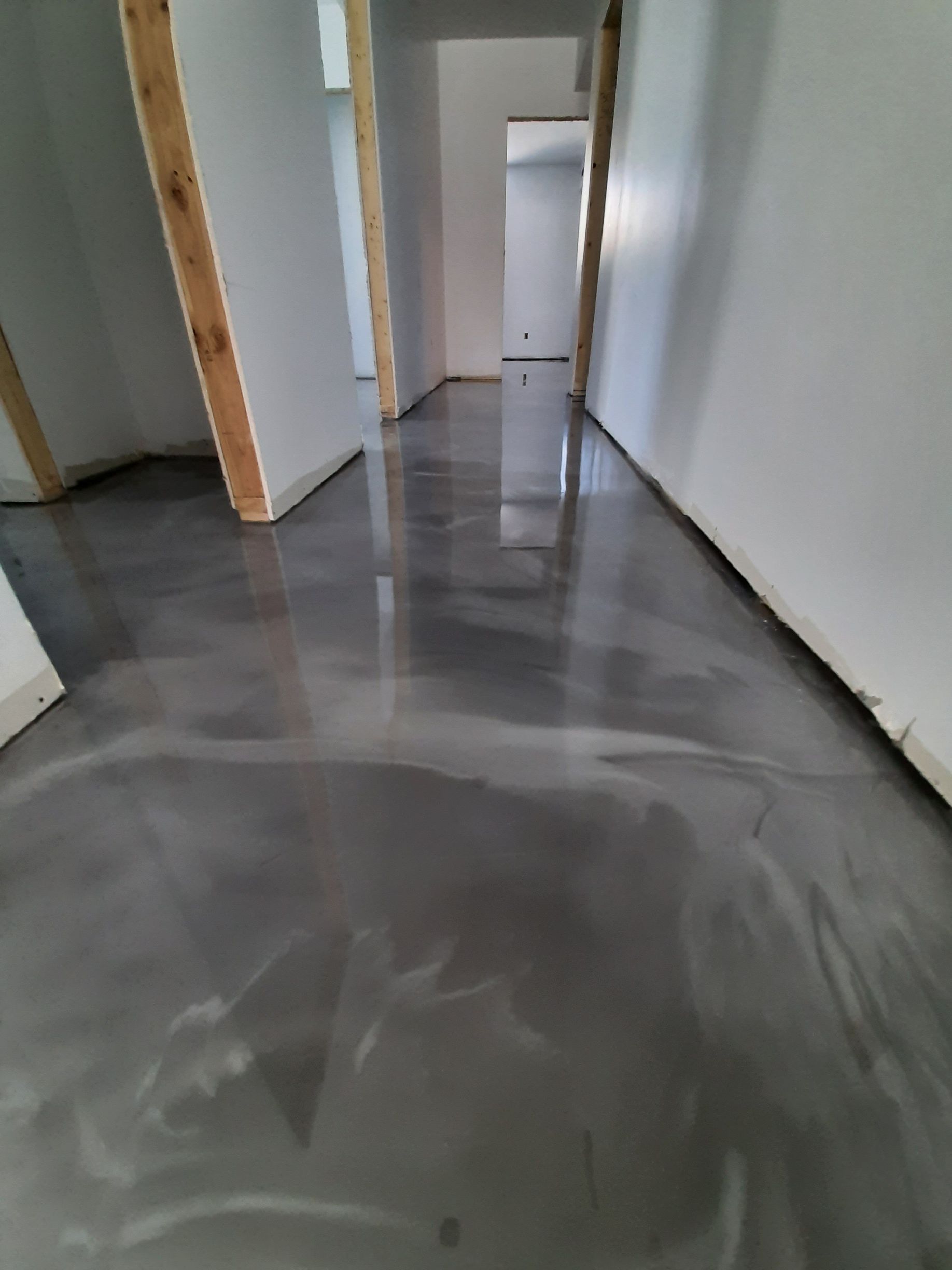 Un couloir avec un sol gris et des murs blancs