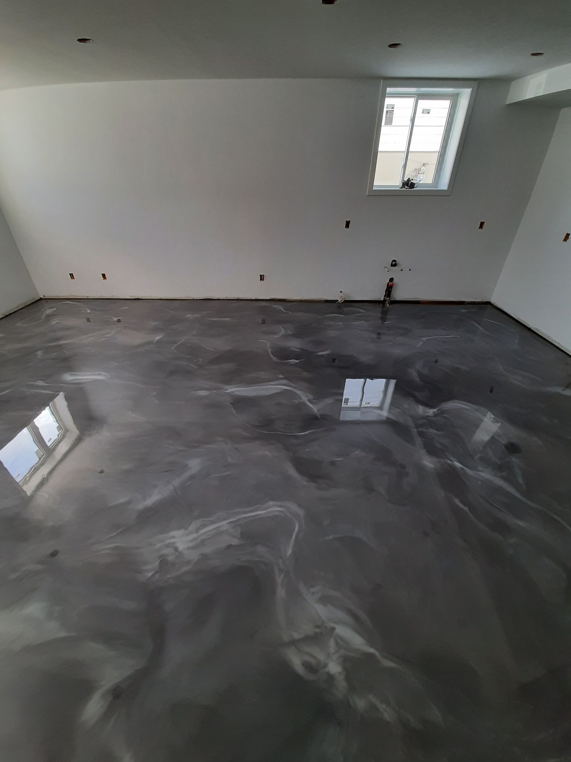 Une pièce avec un sol métallique brillant et une fenêtre.