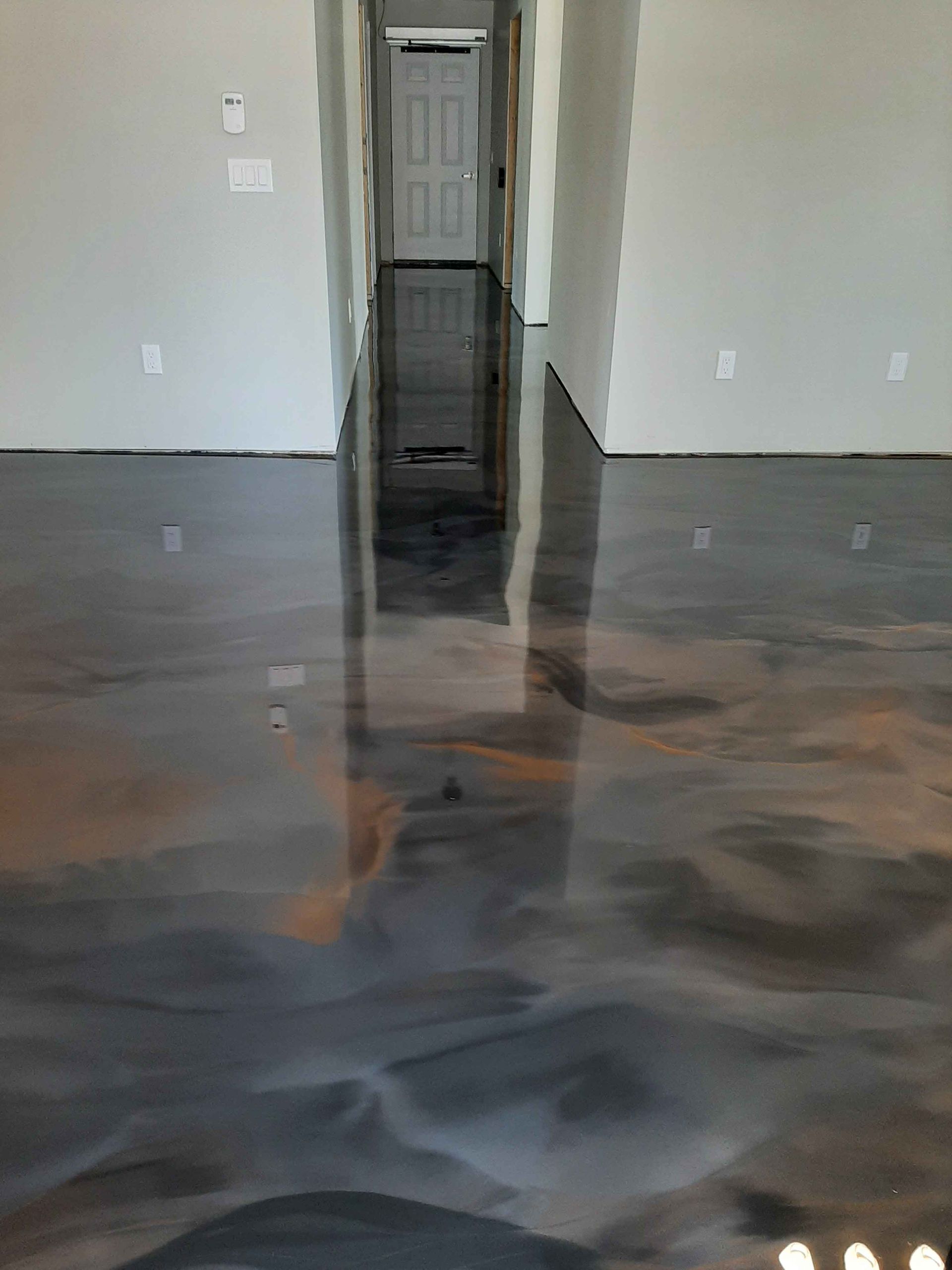 Un salon avec un sol métallique brillant et un couloir.