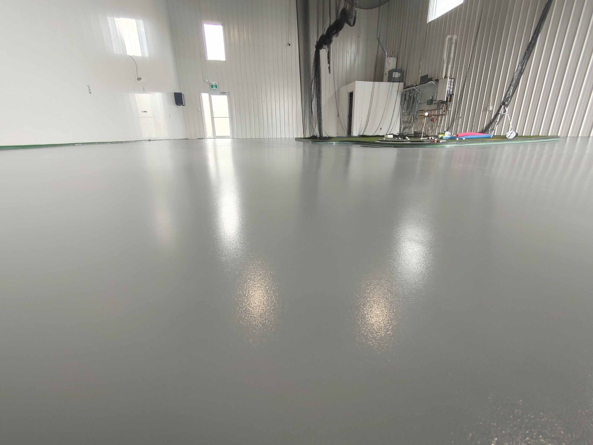 Une grande pièce avec un sol gris et des murs blancs.