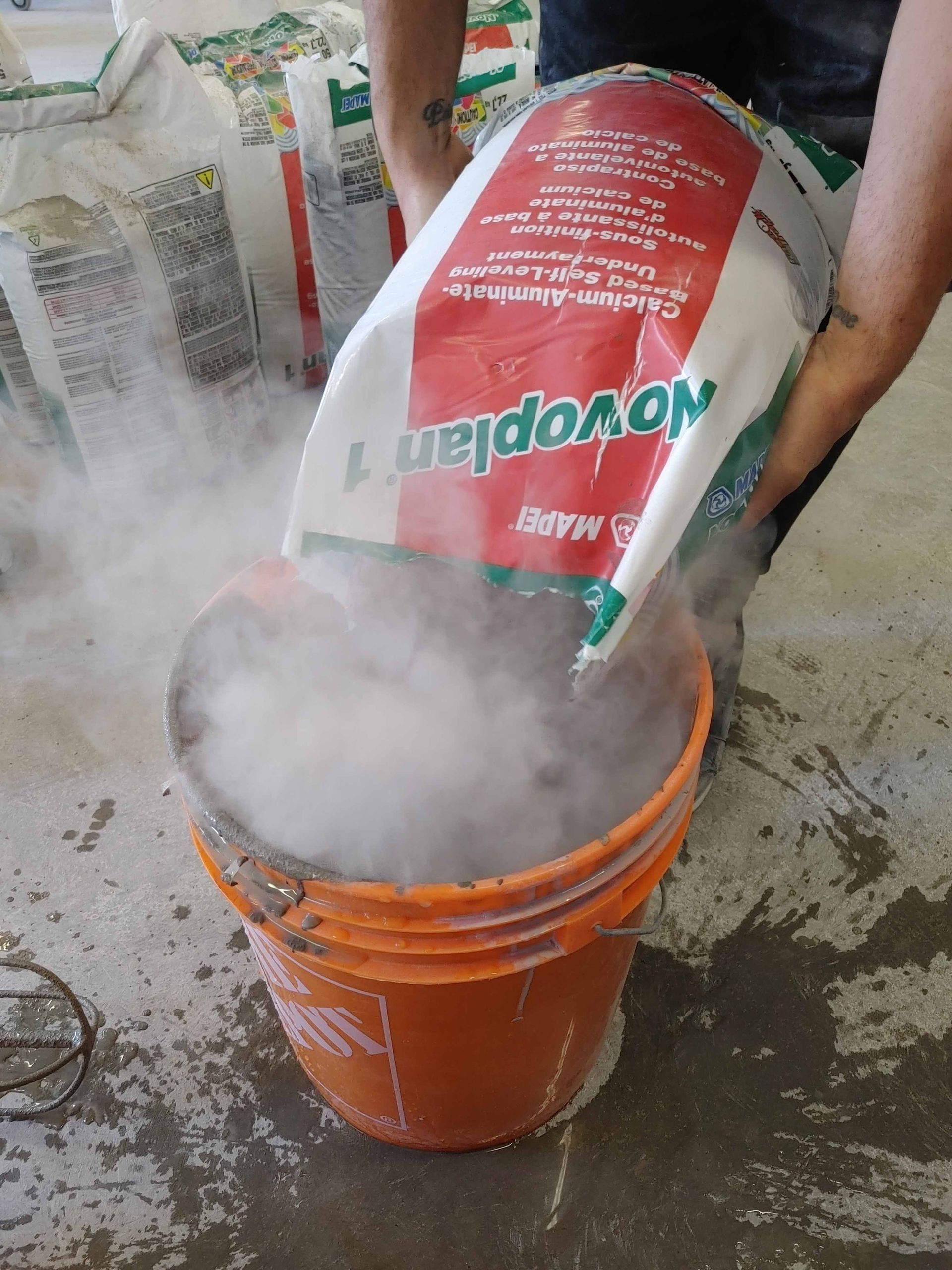 Un sac de novoplan est versé dans un seau orange