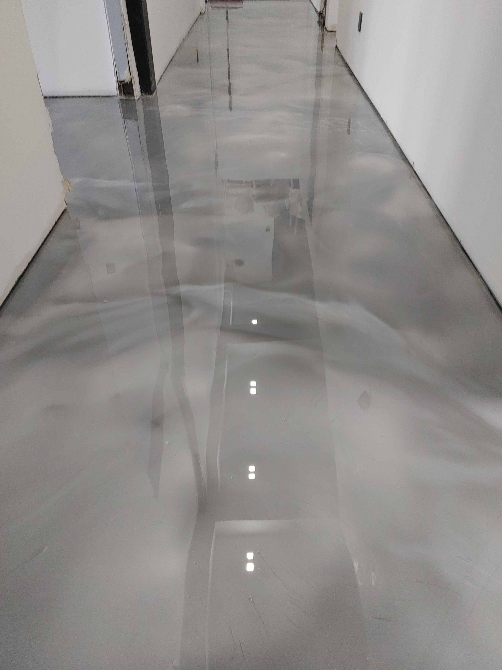 Un couloir avec un sol métallique brillant et des murs blancs.