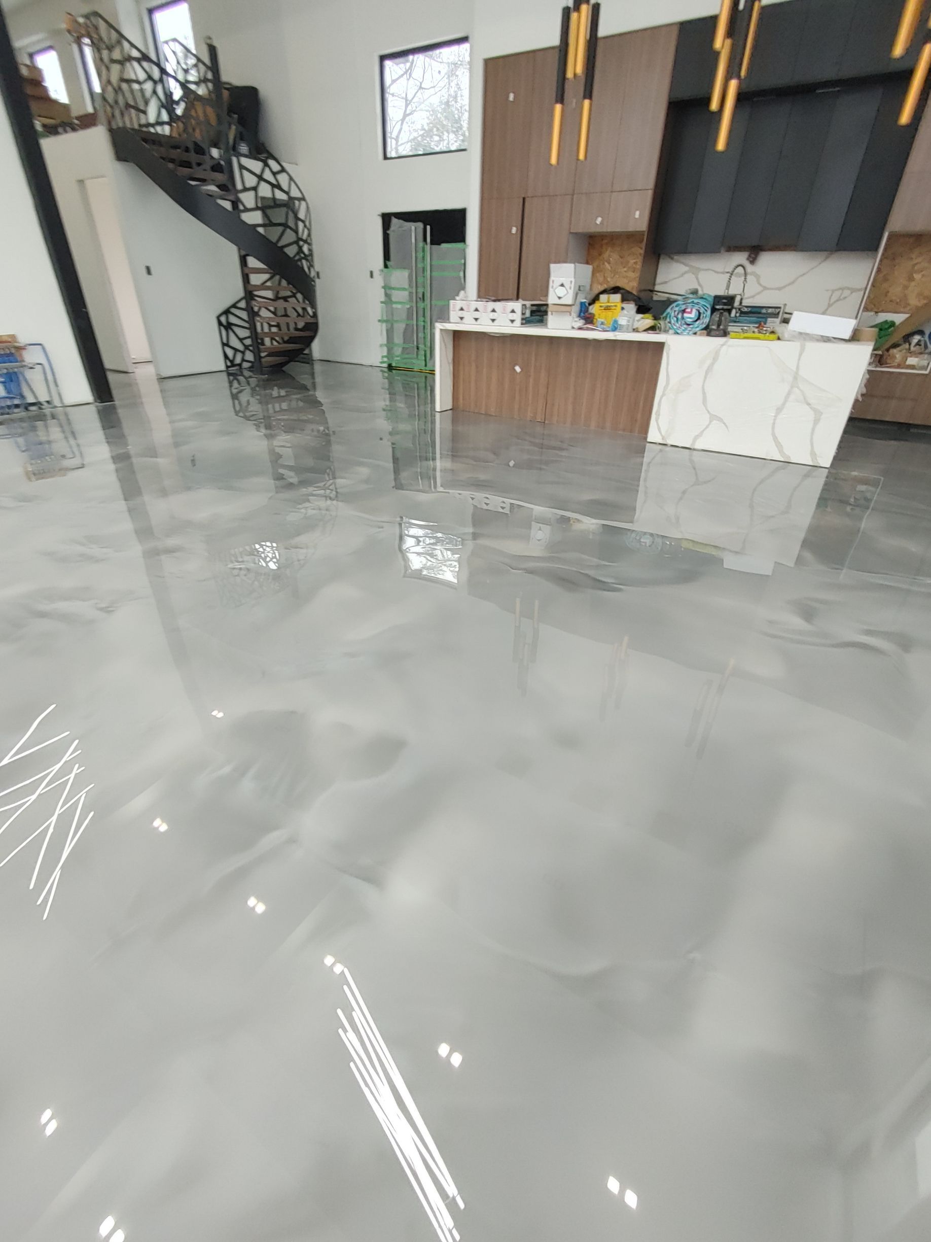 Une cuisine avec un escalier en colimaçon et un sol métallique brillant.