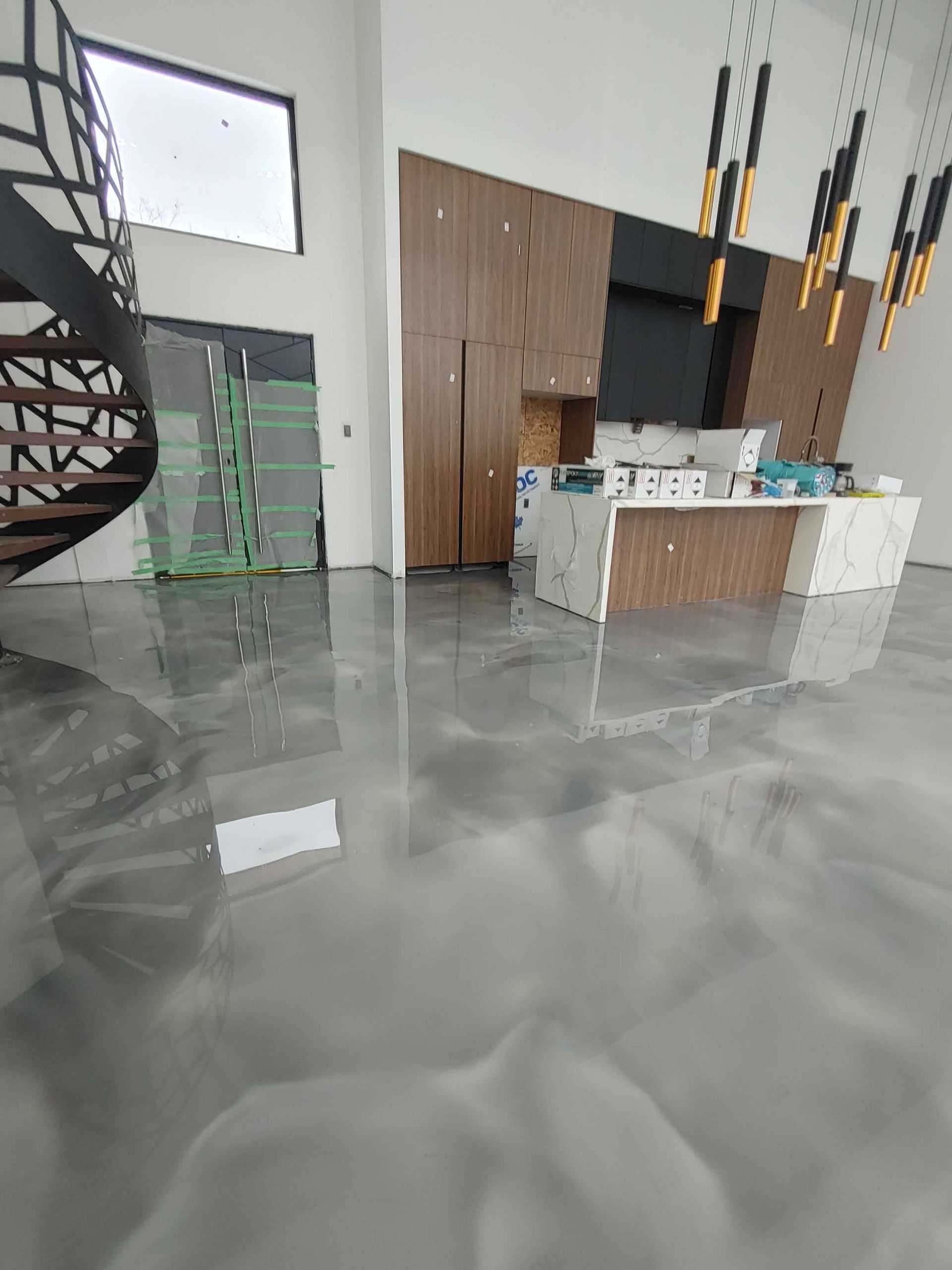 Une cuisine avec un escalier en colimaçon et un sol métallique brillant.