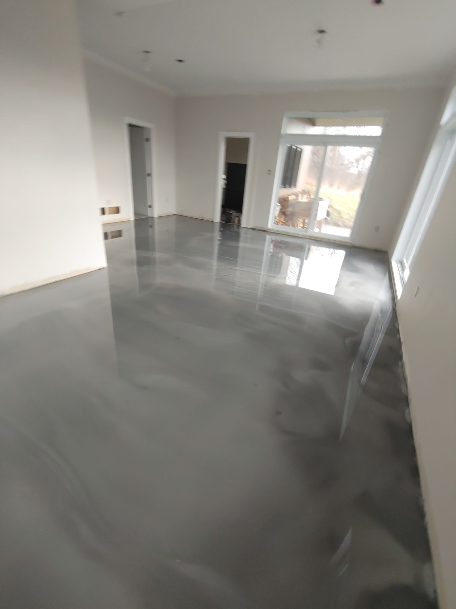 Un salon avec un sol gris métallisé et des murs blancs.