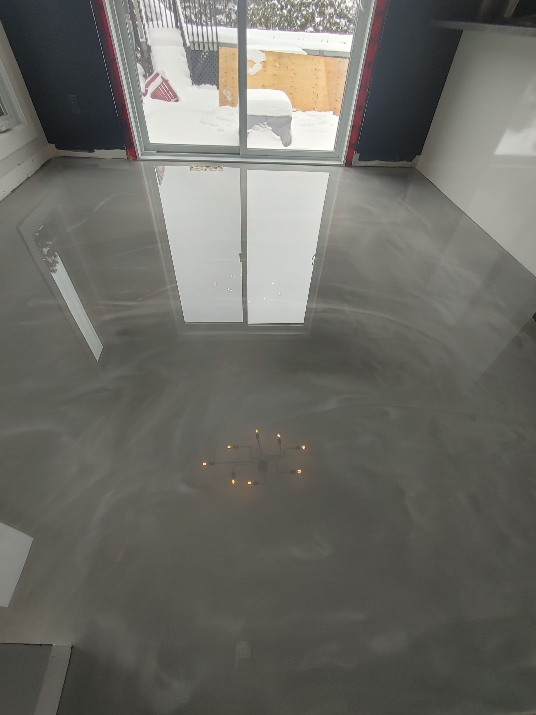 Une pièce avec un sol en béton brillant et une fenêtre.