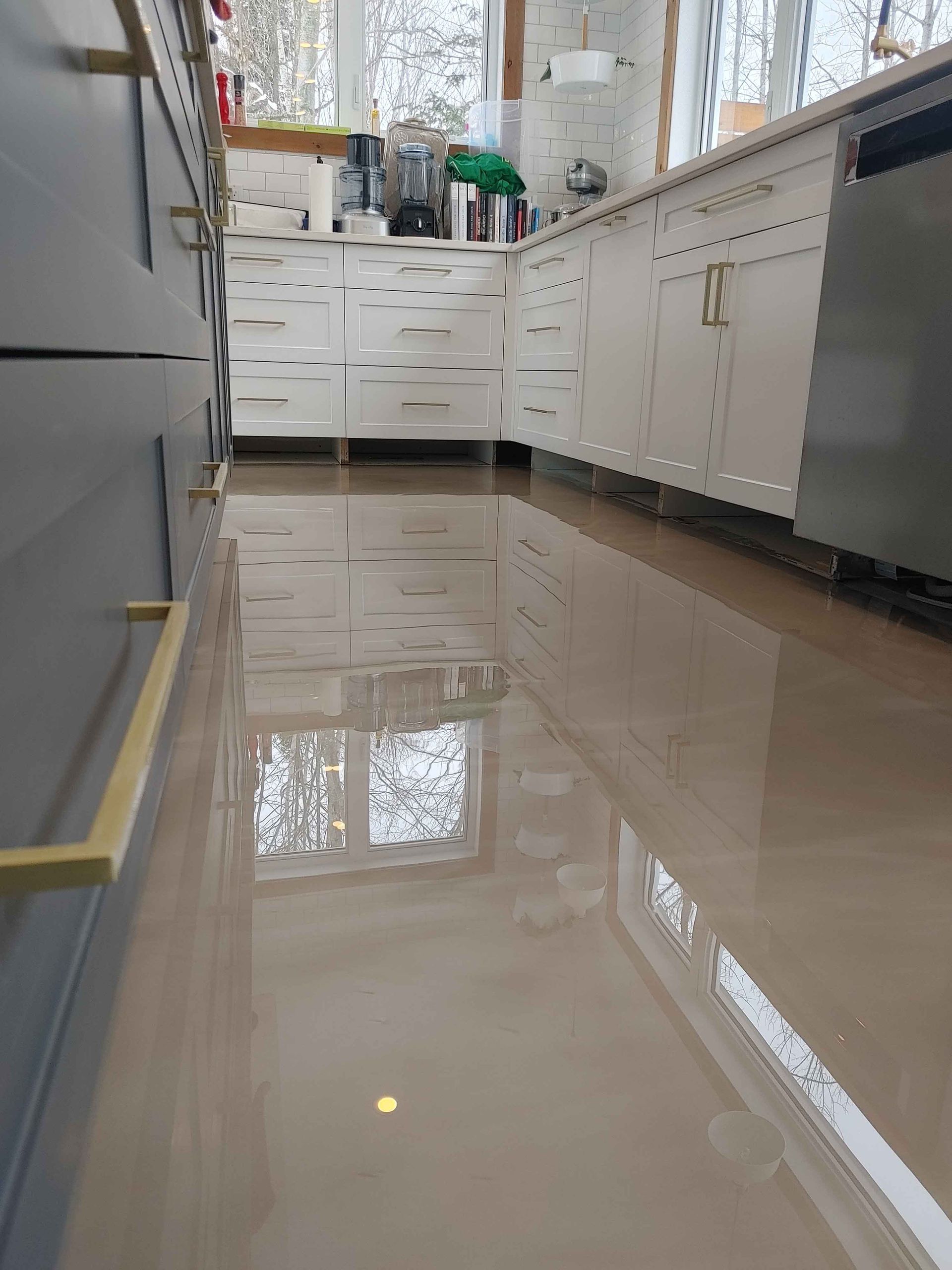 Une cuisine avec des armoires blanches et un sol brillant.