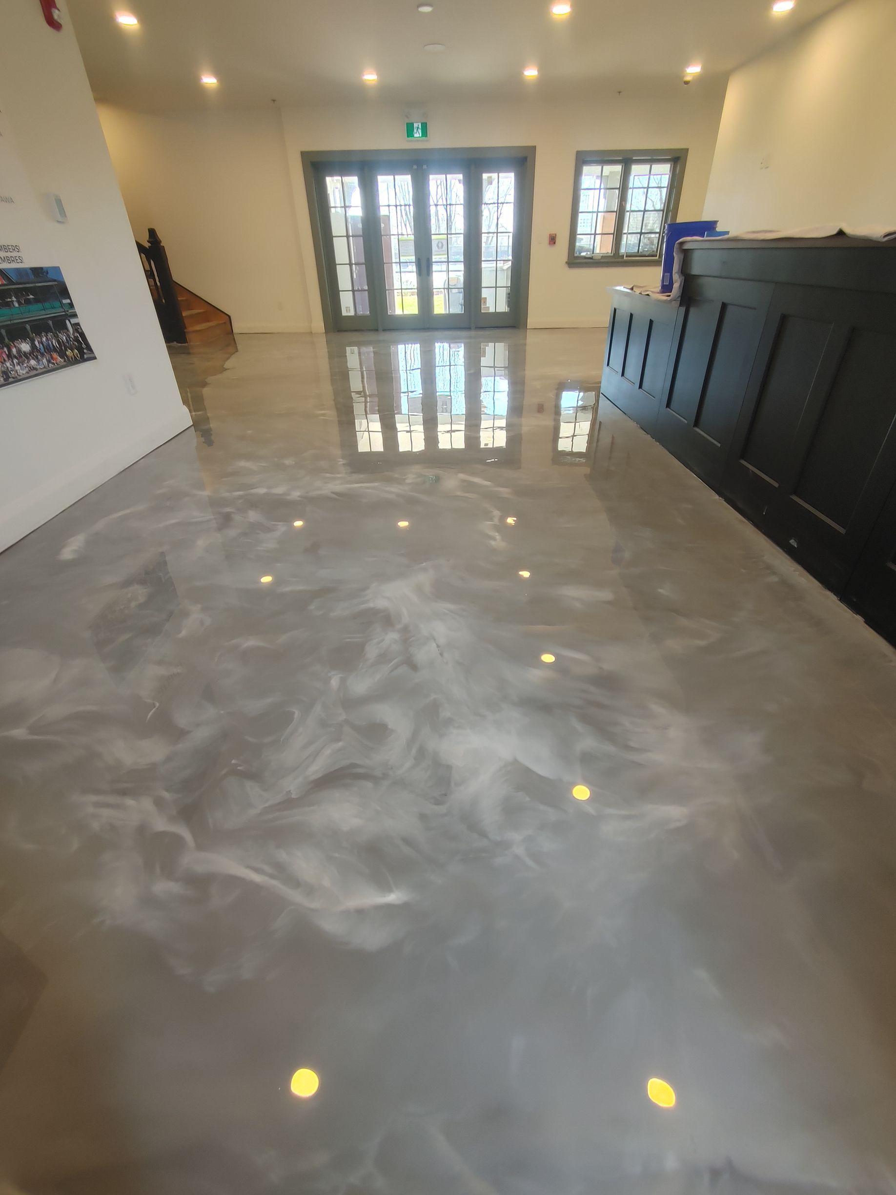 Une grande pièce avec un sol en béton brillant et une grande fenêtre.