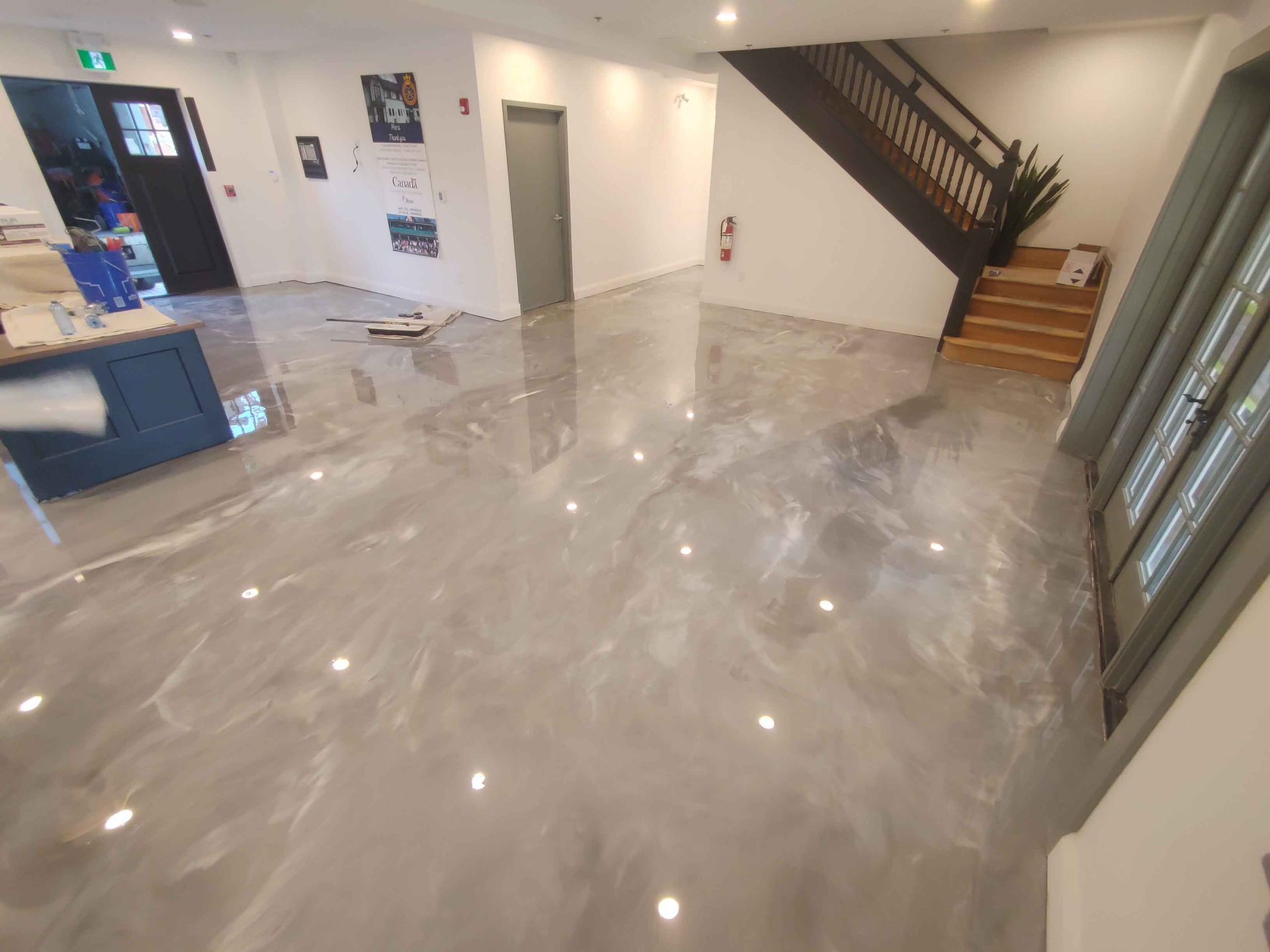 Une grande pièce avec un escalier et un sol brillant.