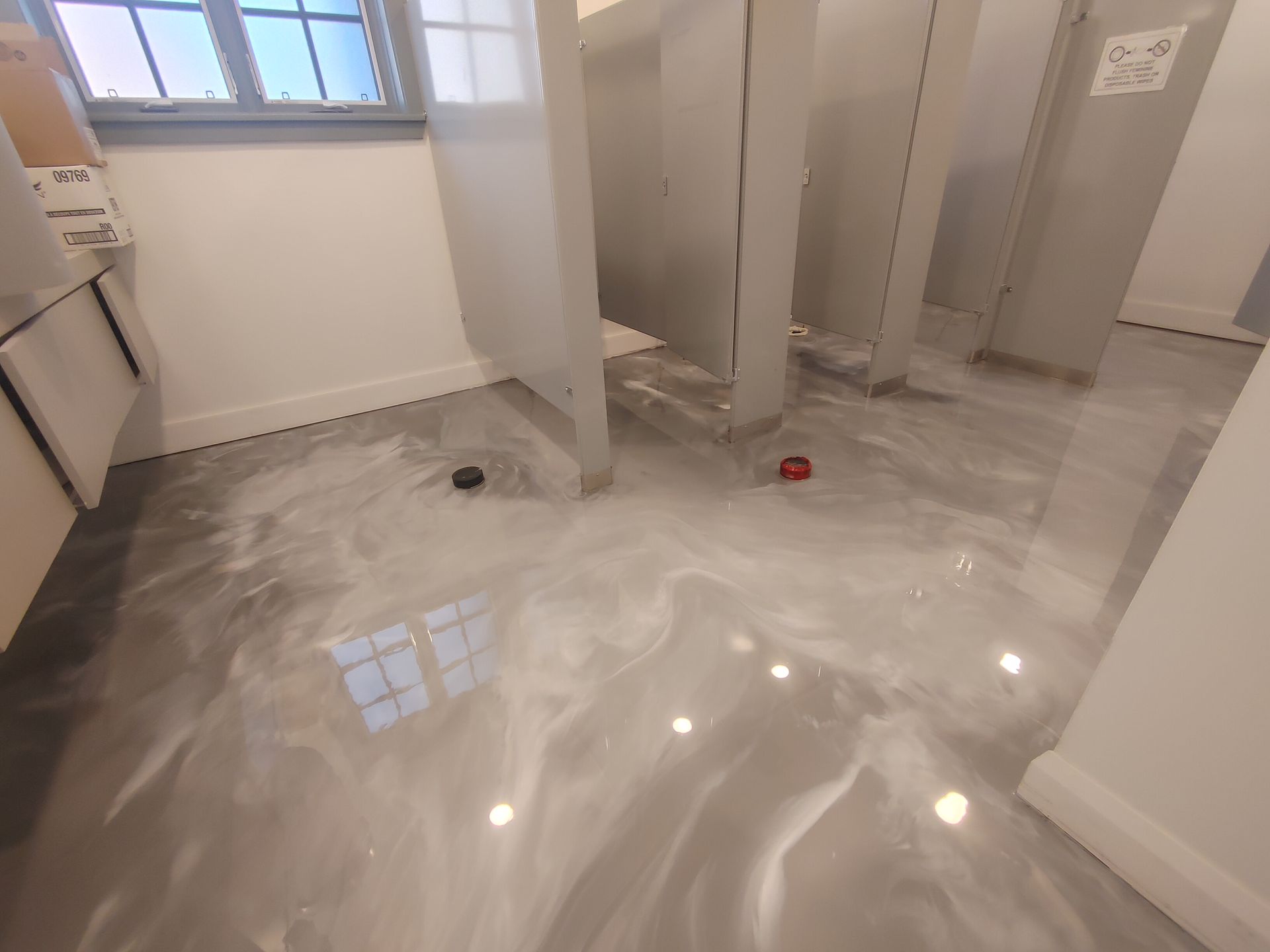 Une salle de bain avec un sol brillant et une fenêtre.