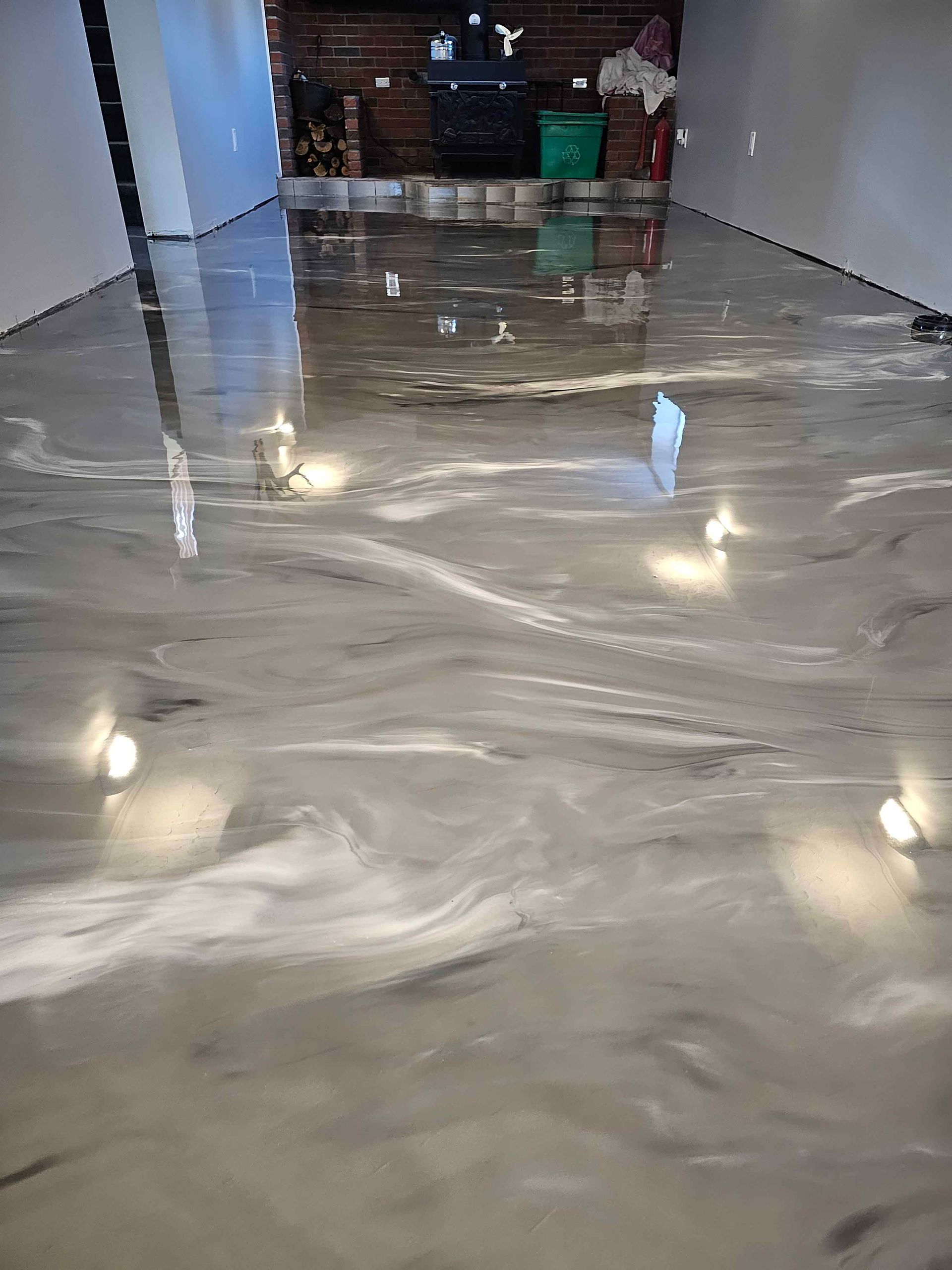 Un sol métallique brillant dans un sous-sol avec une cheminée en arrière-plan.