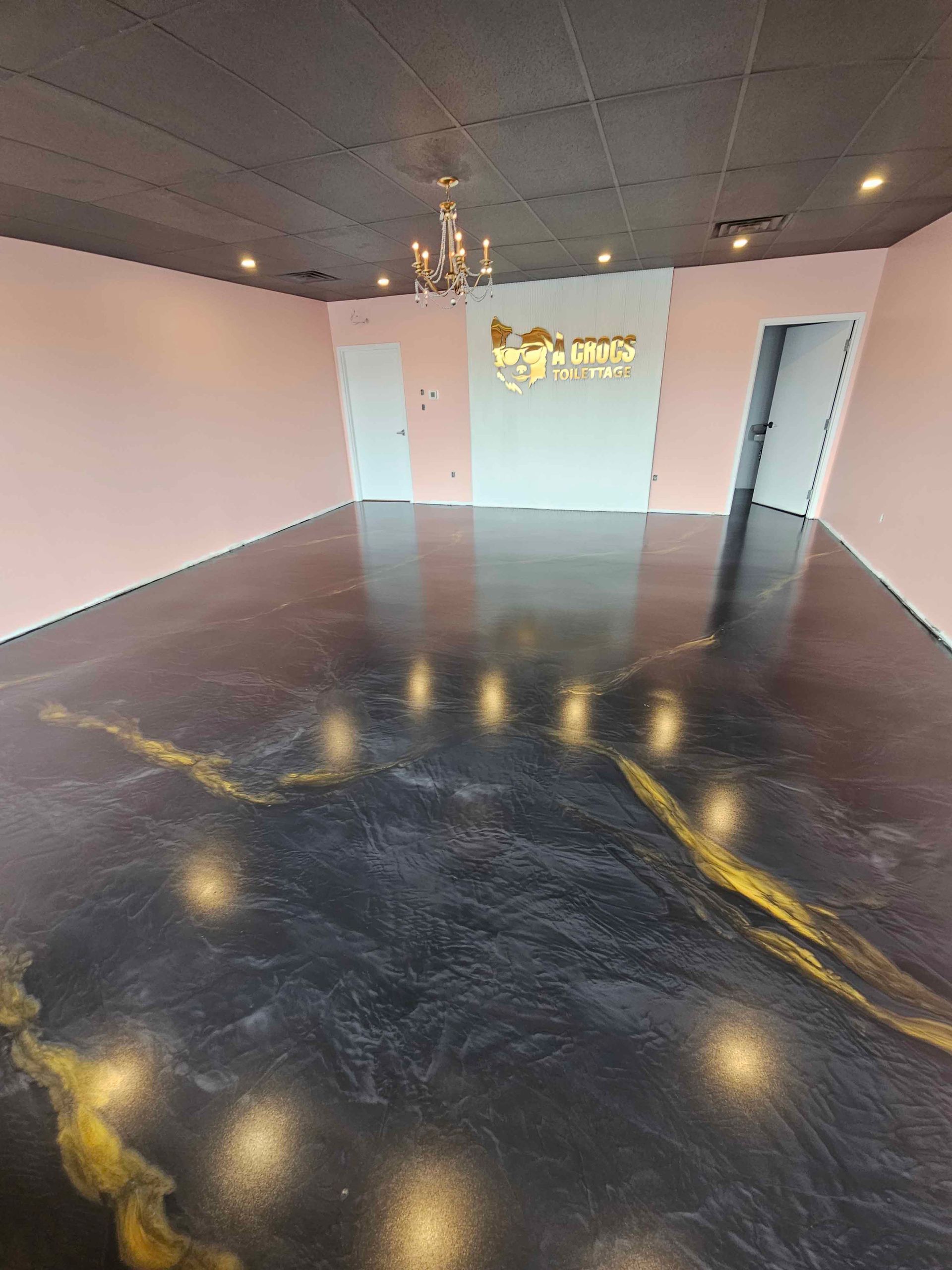 Une grande pièce avec un sol noir et un lustre.