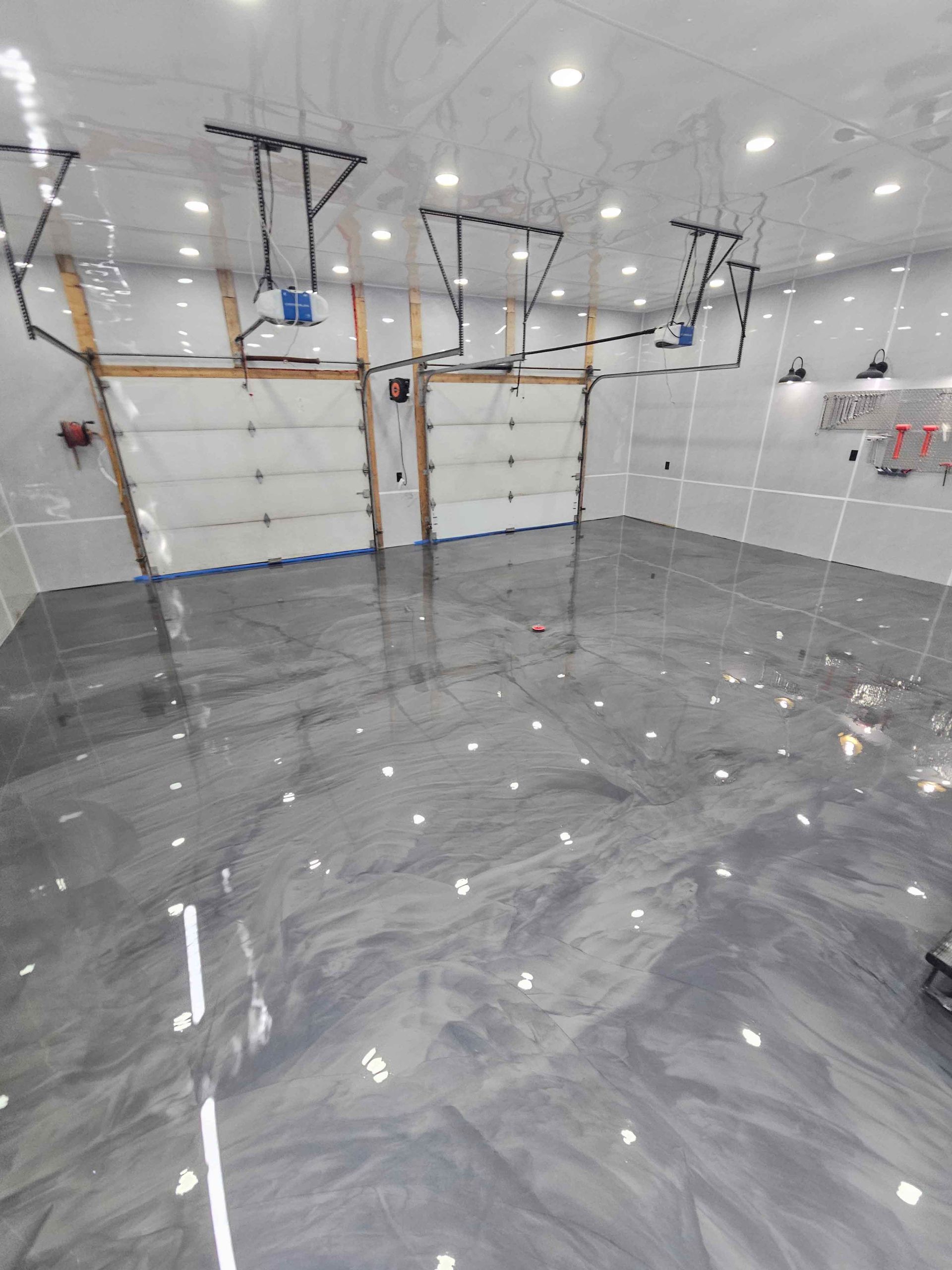 Un garage avec un sol métallique brillant et deux portes de garage.