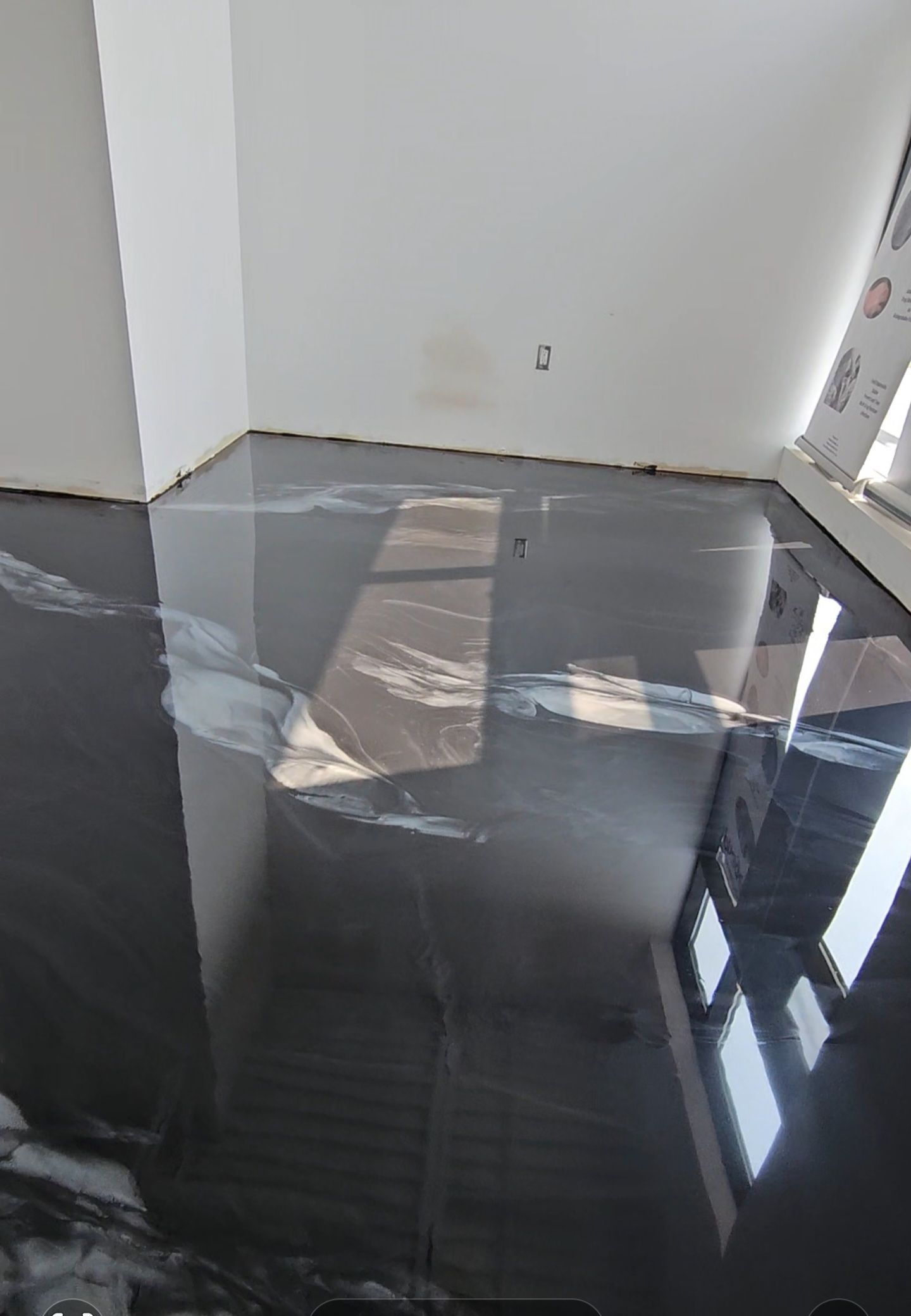 Une pièce avec un sol métallique noir et des murs blancs.