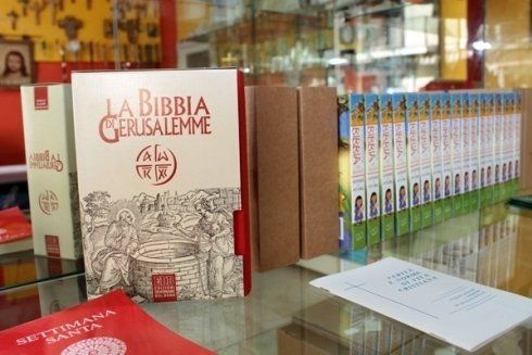 Una Bibbia è appoggiata su uno scaffale di vetro accanto ad altri libri