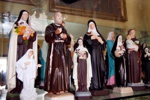 Un gruppo di statue di santi sono esposte su una mensola di vetro