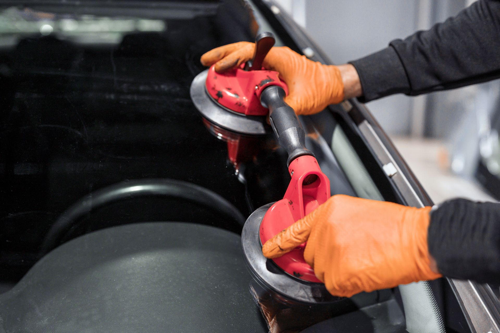 Close-up of an auto repairman fixing the windshield of a car.