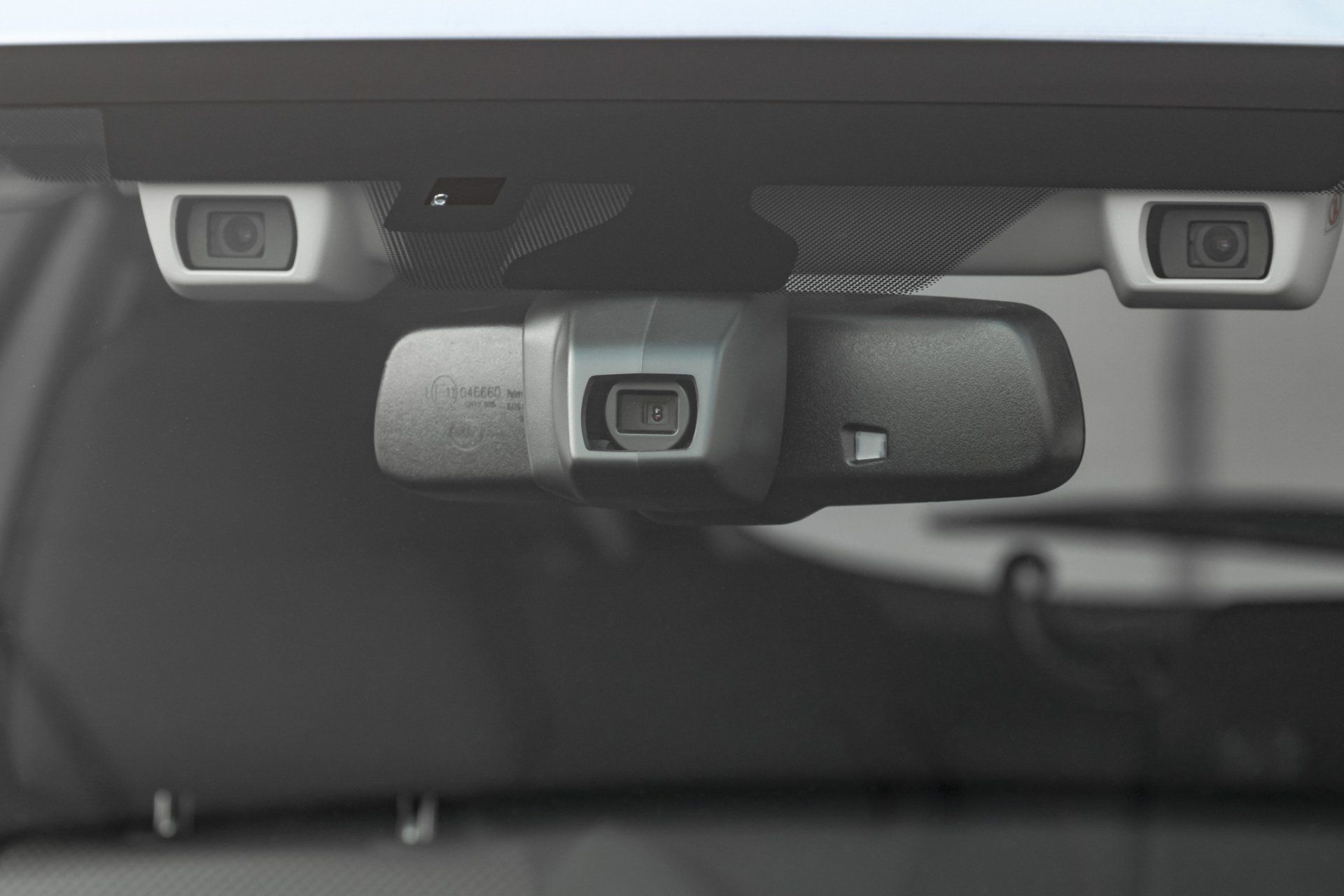Close-up of a car's interior, showing the rearview mirror and two cameras for driver-assistance systems mounted on the windshield.