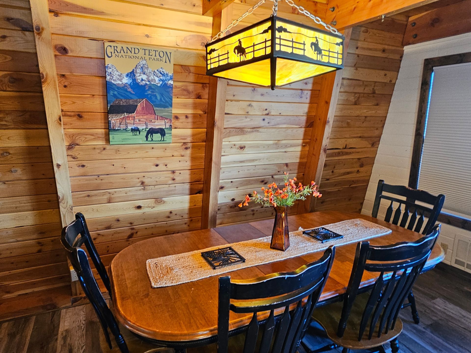 Dining area: wooden table, chairs, art, and a decorative light fixture.