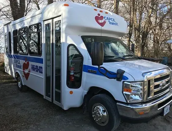a white and blue bus with a heart on the side is parked in a parking lot.