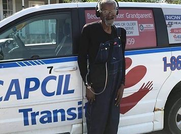 a man wearing headphones is standing in front of a capcil transit van
