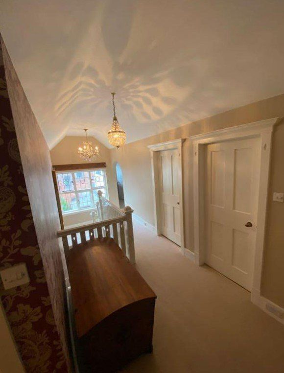 A hallway with a wooden chest of drawers in the middle of it.