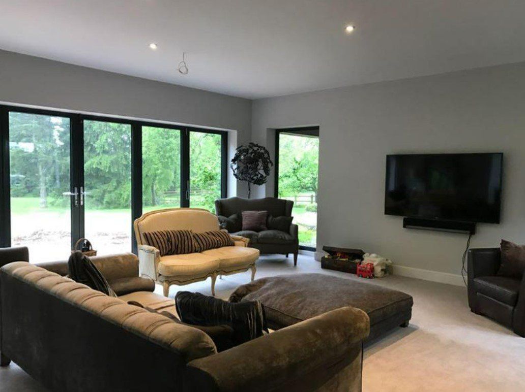 Picture of a living room with bi-folding doors painted in white with tv hung on the feature wall by painters and decorators Glasgow