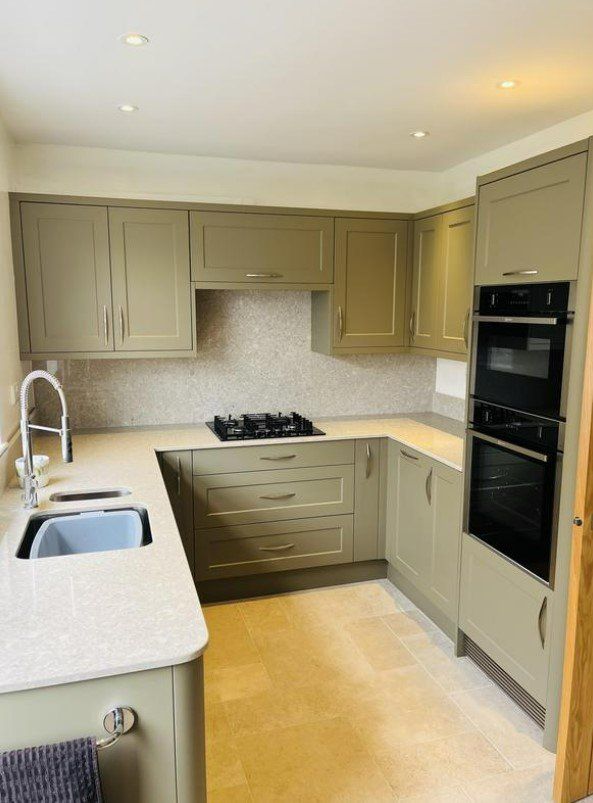 A picture of a kitchen with sage green units decorated by the painting and decorating Glasgow team