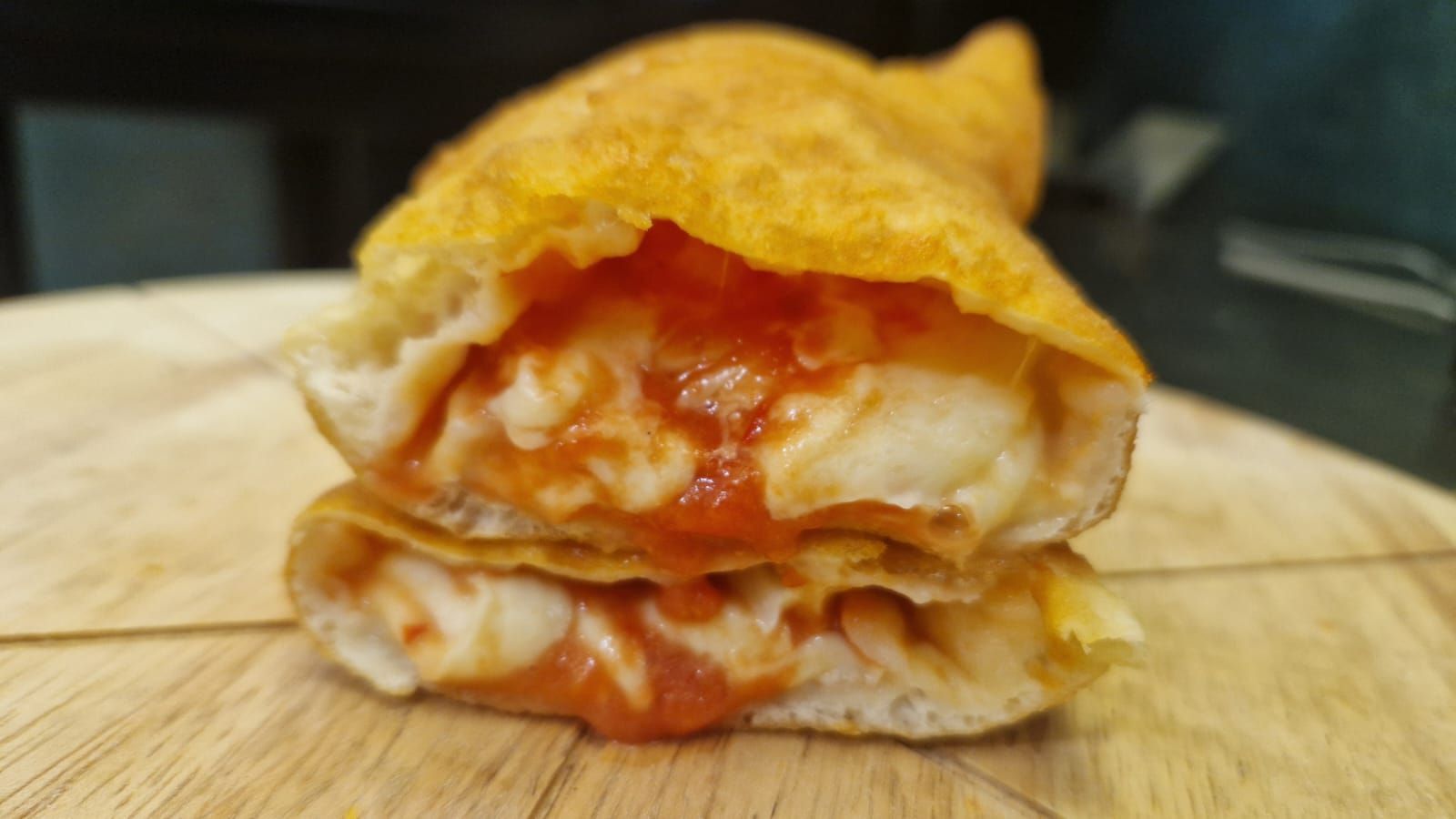Calzone fritto tagliato a metà, che rivela mozzarella fusa e salsa di pomodoro.