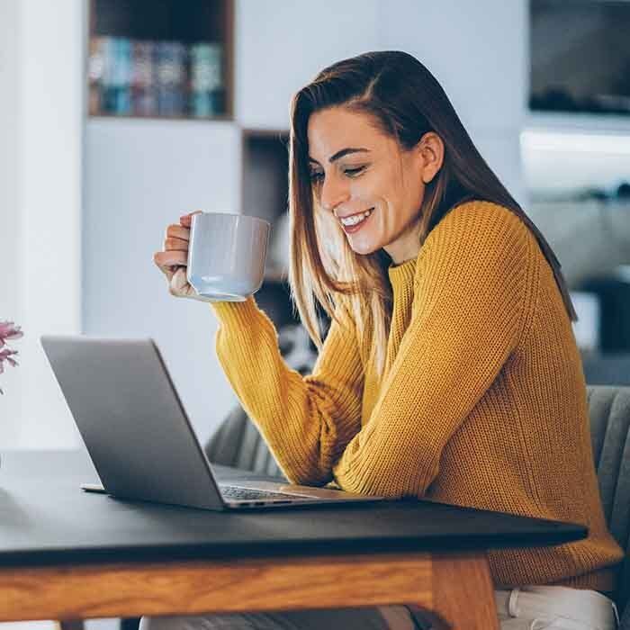 Woman Having A Coffee While Looking At Laptop — United States — NextGen Financial Advice