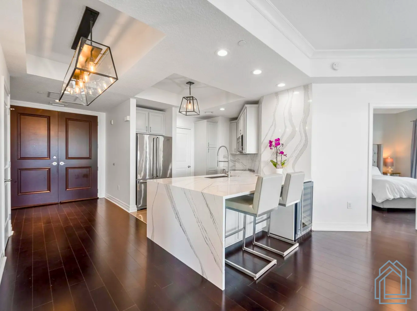 Modern kitchen and dining area with white island, dark wood floors, and stainless steel appliances