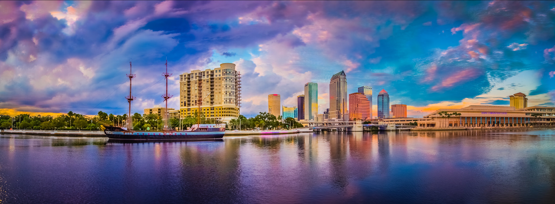 A vibrant sunset sky with purple and blue clouds over a Tampa, Florida, city skyline and waterfront.