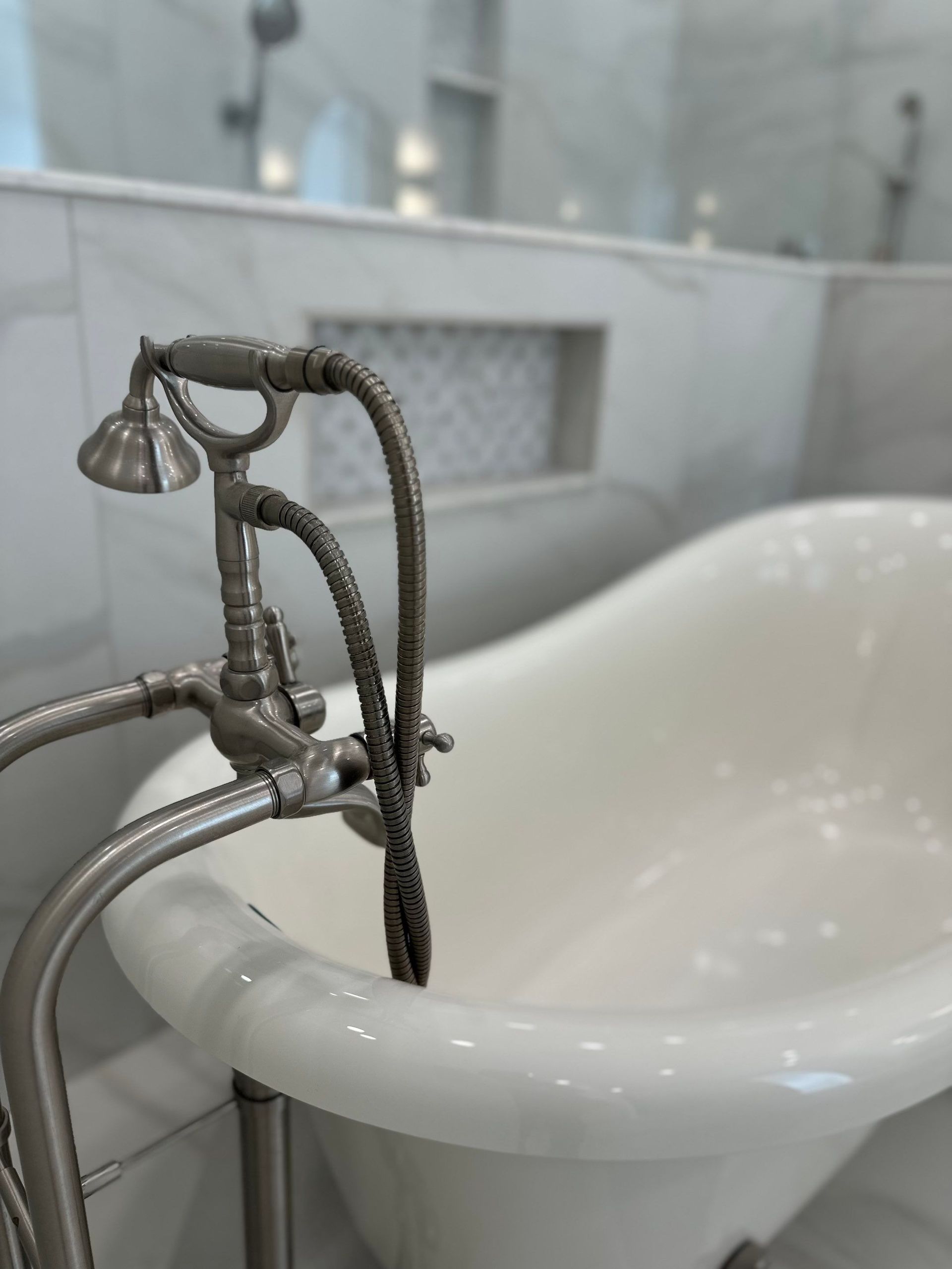 Decorative silver faucet beside a white freestanding bathtub in a bright bathroom