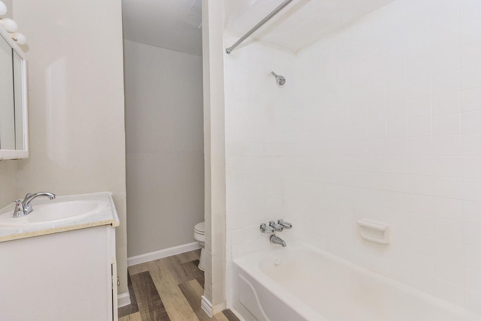 Bathroom with sink, vanity, mirror, and a white tiled bathtub/shower.
