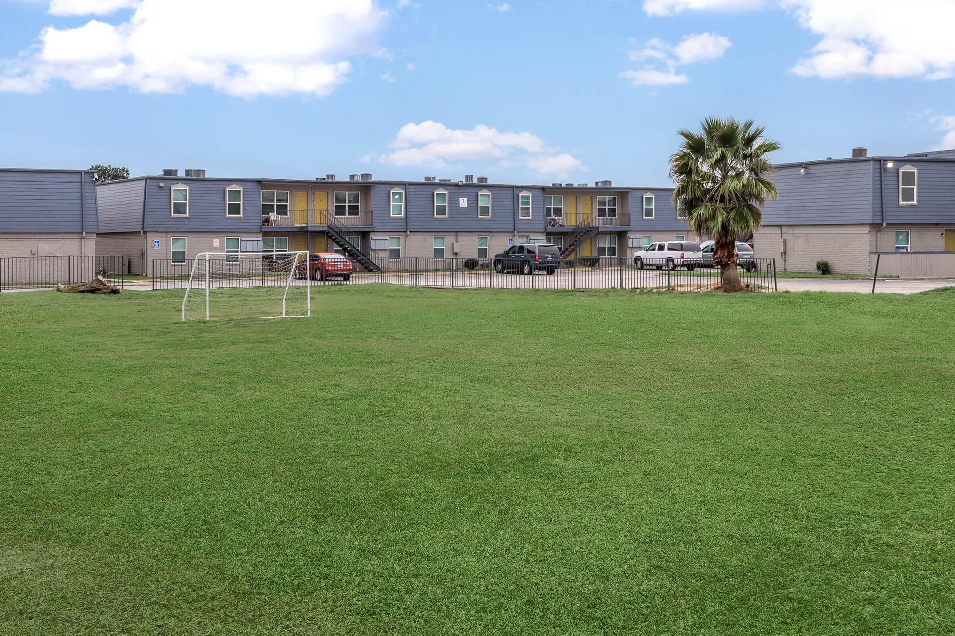 Exterior view of a multi-family community with a grassy lawn and a small soccer goal.