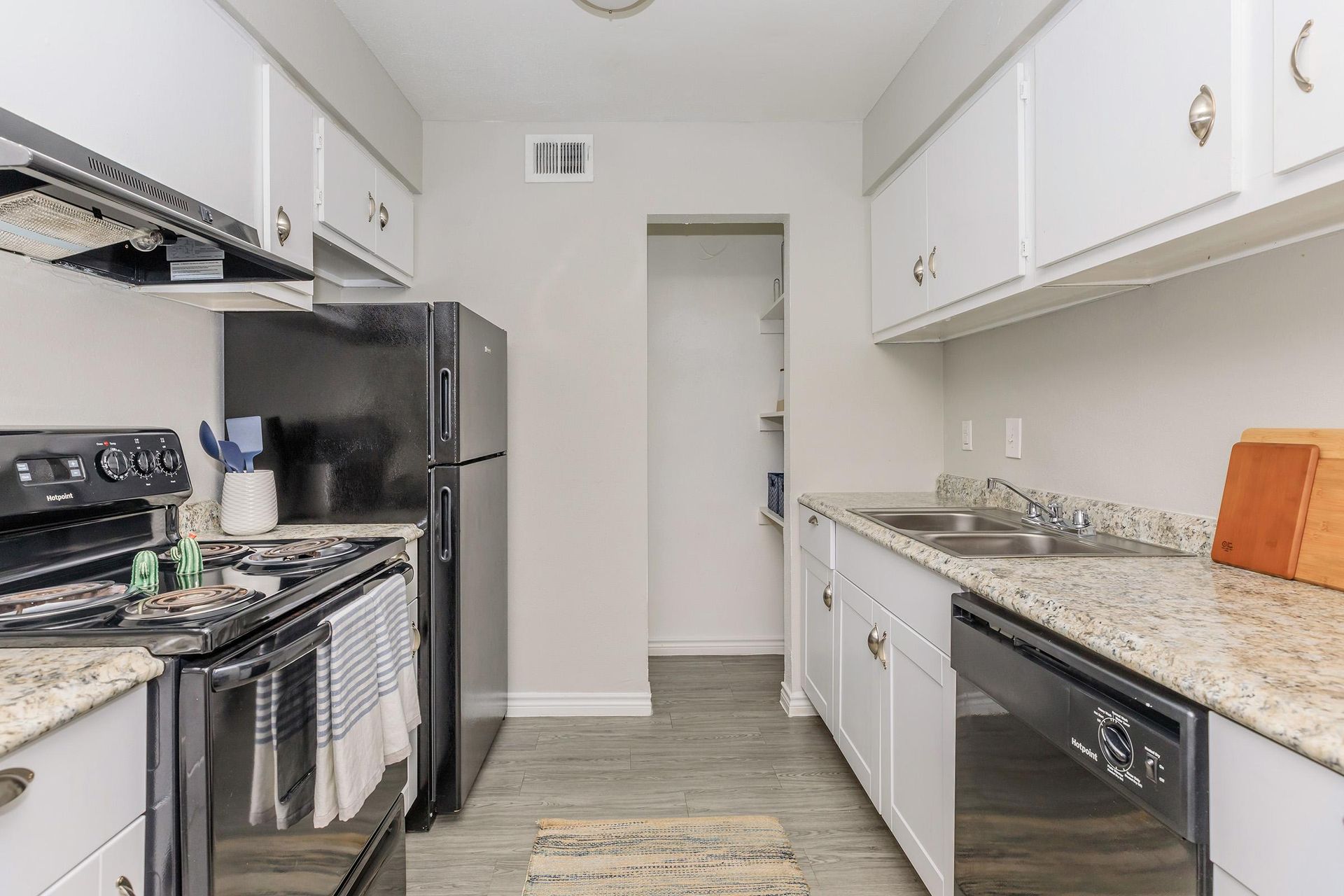 Kitchen in an apartment with white cabinets, granite countertops, and stainless steel appliances.