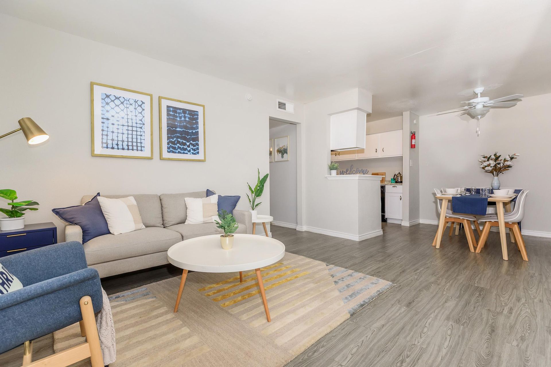 Open living room and dining area in a modern apartment with a gray sofa, round coffee table, and dining set.