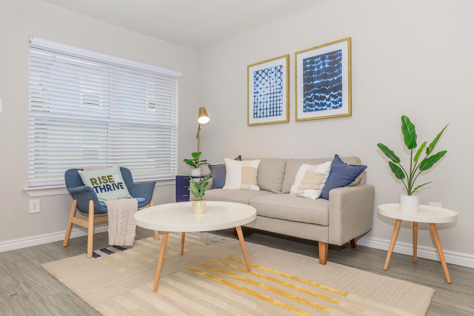 Bright modern apartment living room with sofa, chair, coffee table, and plants.