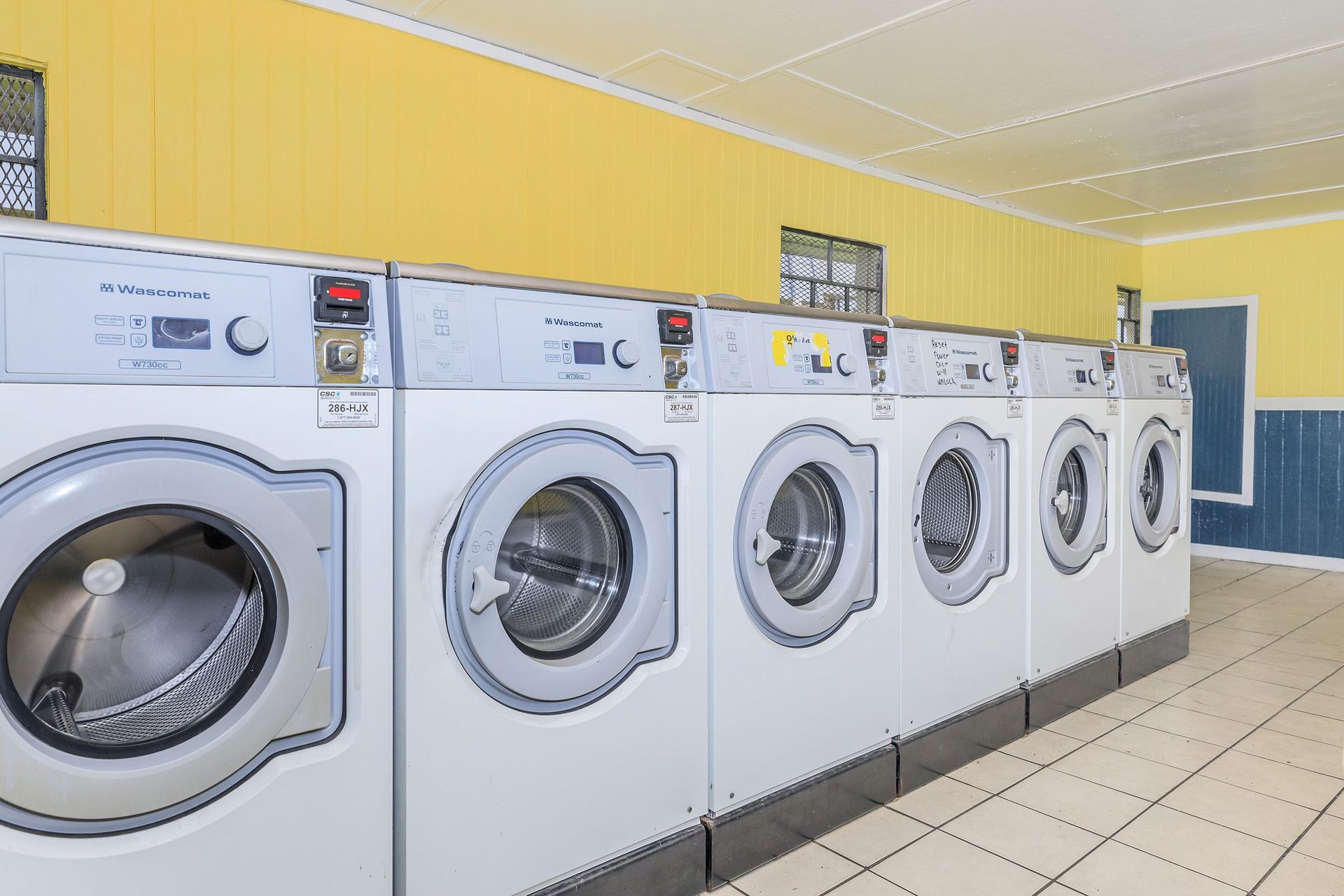 Row of front-loading washing machines in a communal laundry room